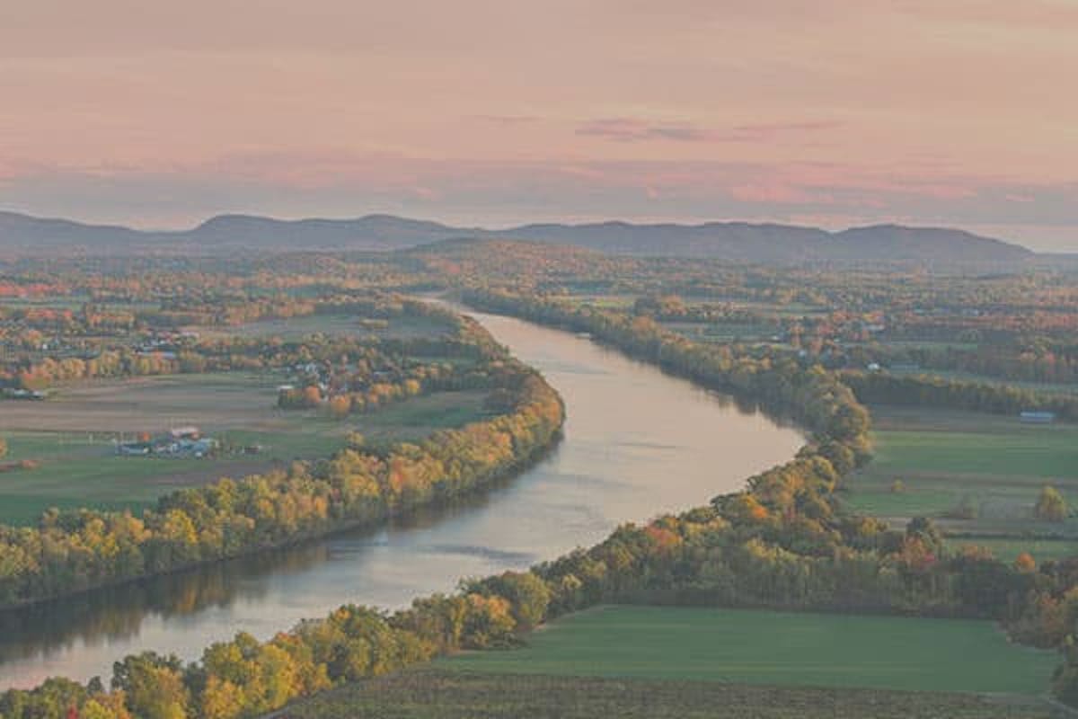 The bend of a river lined with trees and green fields