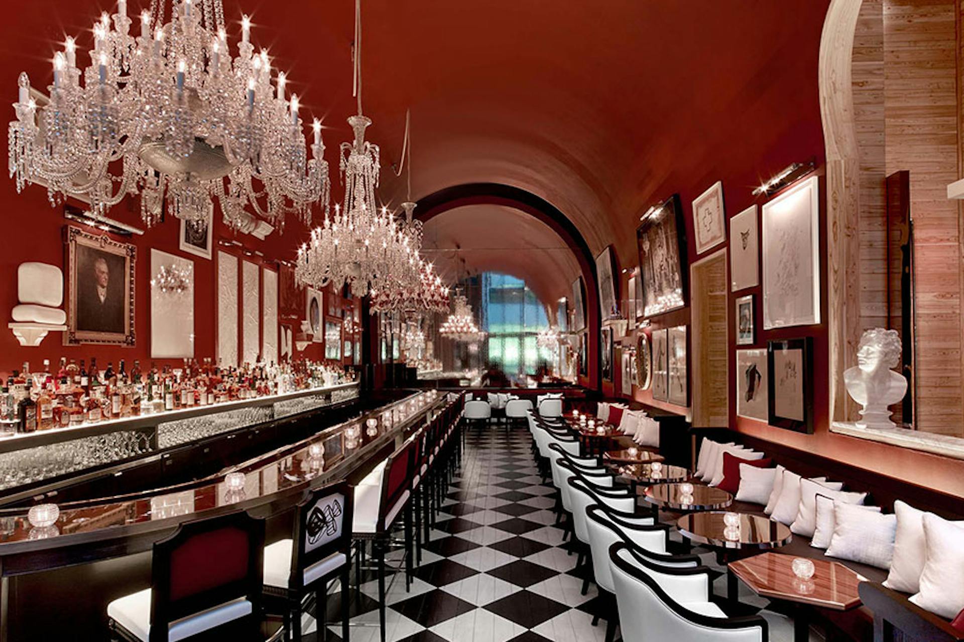 ornate hotel bar with checkered floor, vibrant walls and decorations and black and white seats