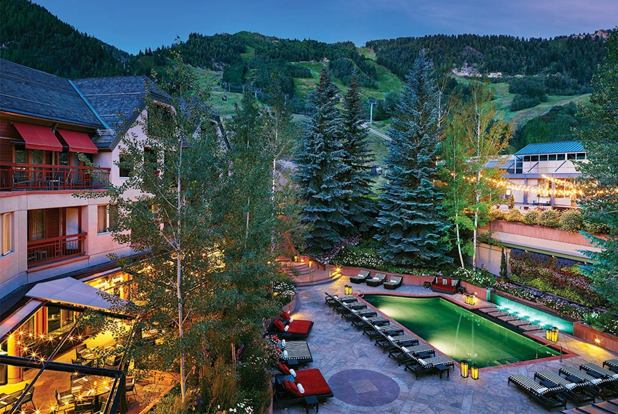 Little Nell hotel courtyard with green trees and inviting pool nestled in the mountains