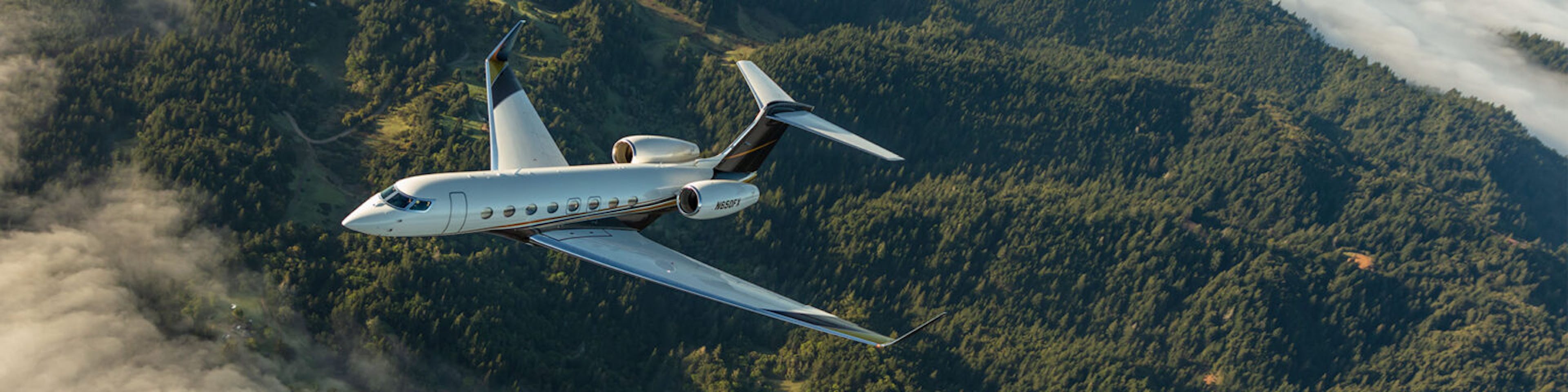 A flexjet aircraft flies over tree covered mountains