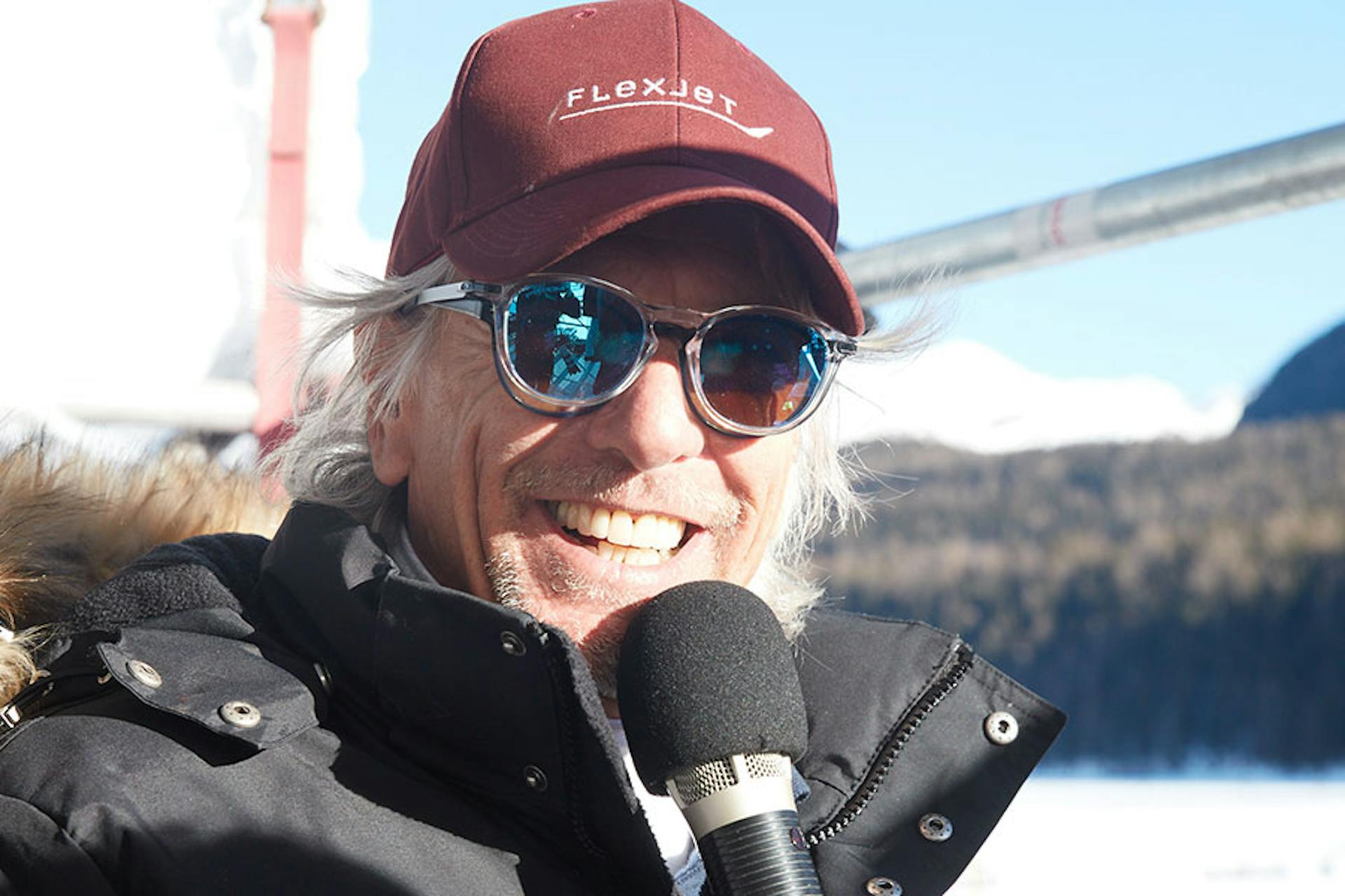 Man in winter with sunglasses and a maroon flexjet hat