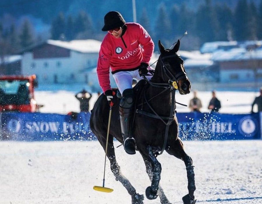 Patrick Paillol reaching down with the mallet during a snow polo match