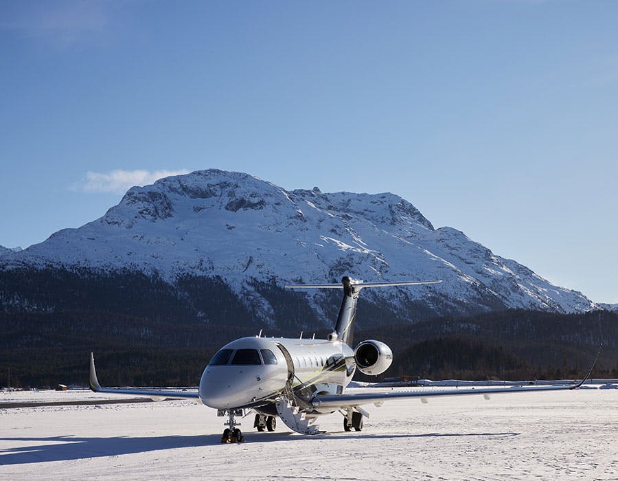 Aircraft on snow covered tarmac and snow capped mountains in the background
