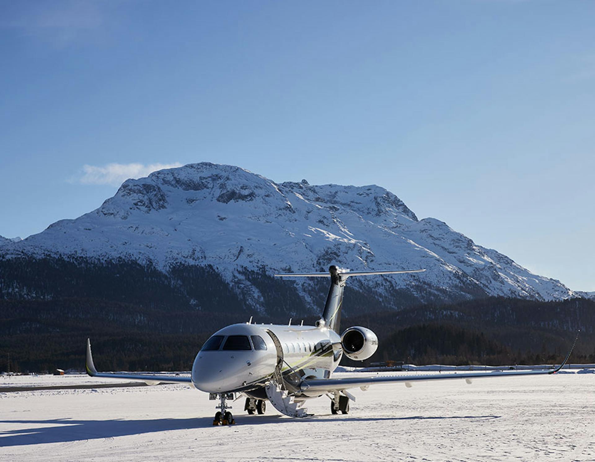 Aircraft on snow covered tarmac and snow capped mountains in the background