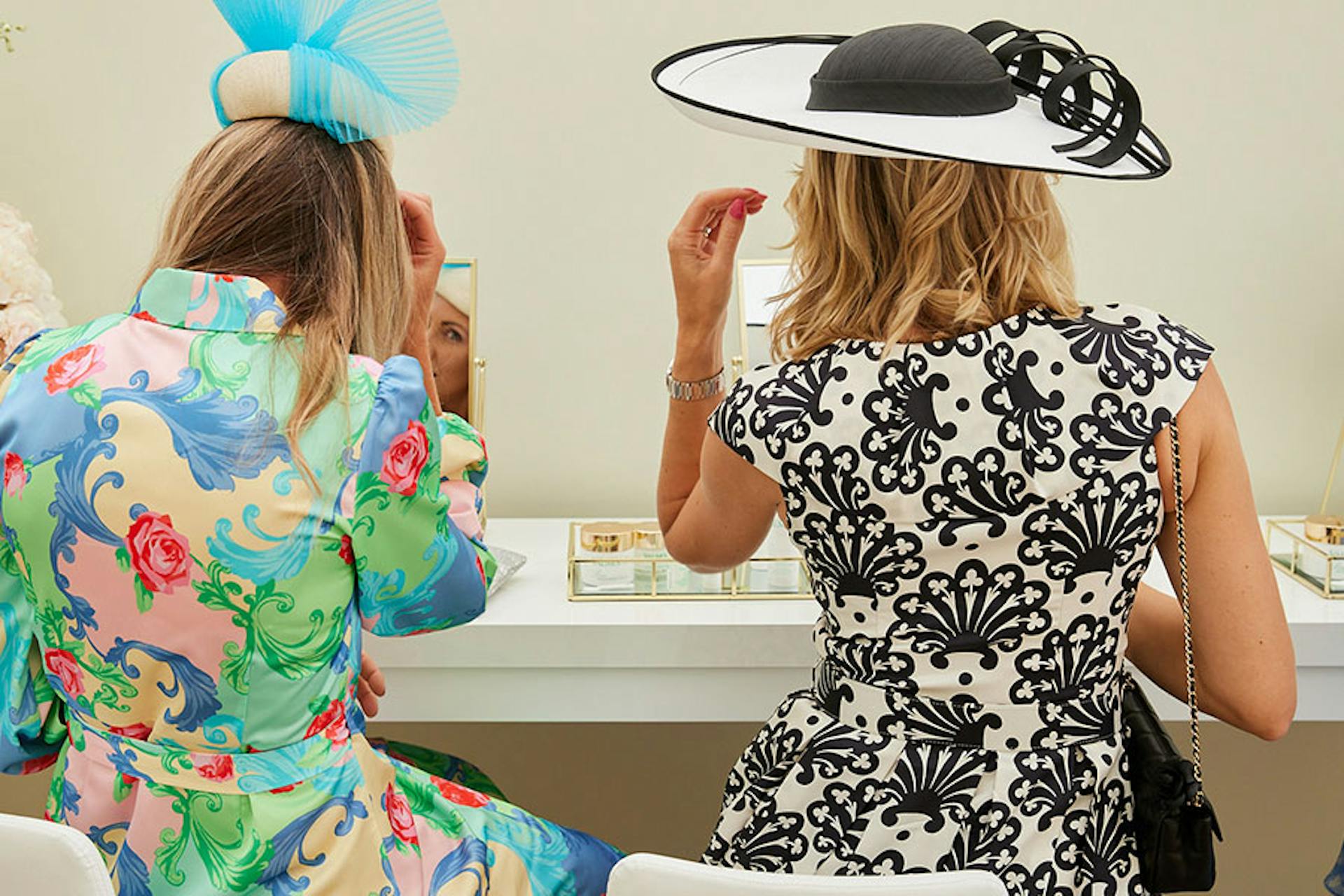 two woman sitting at mirrors touching up their makeup