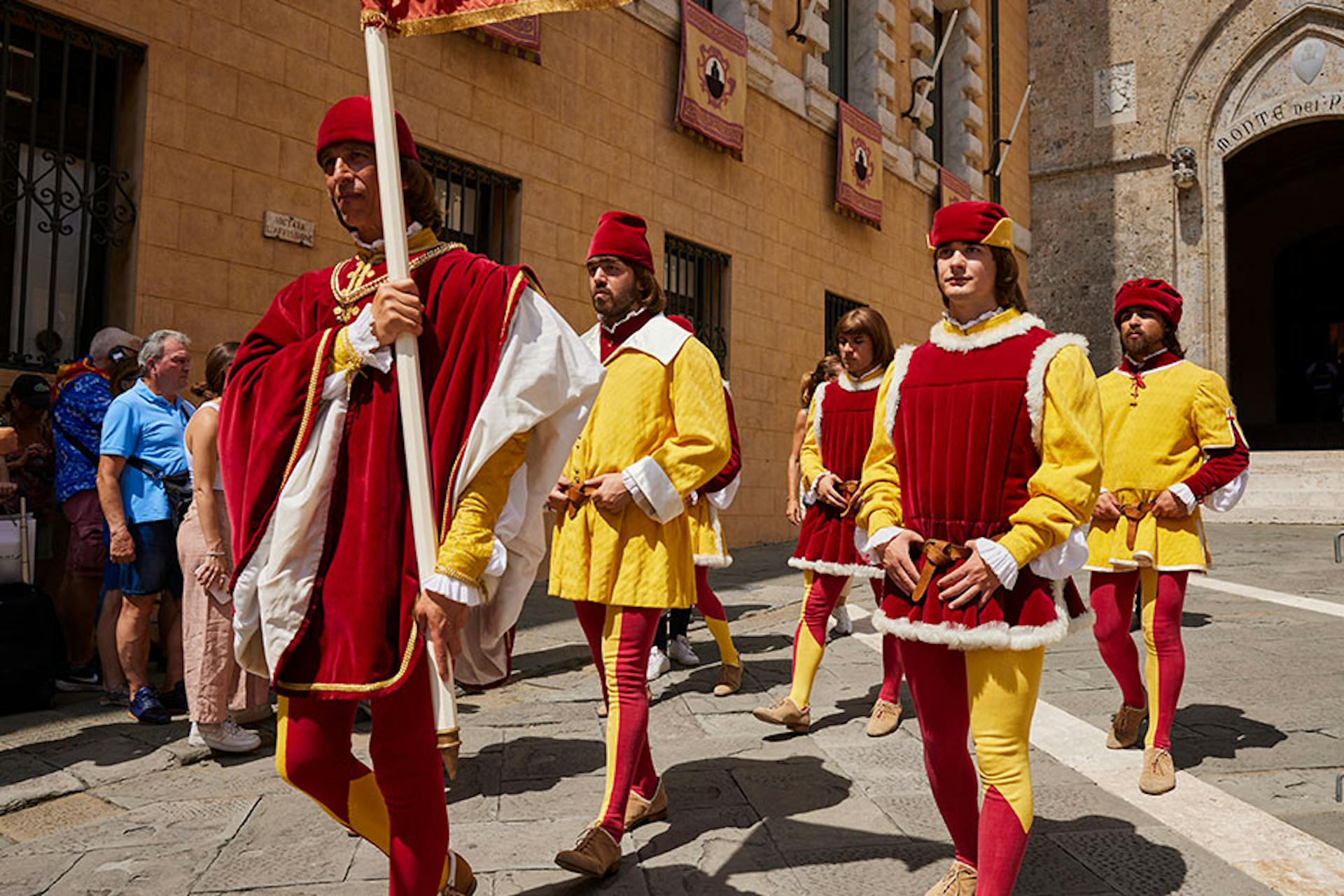 Small group of people in red and yellow costumes parade down a street