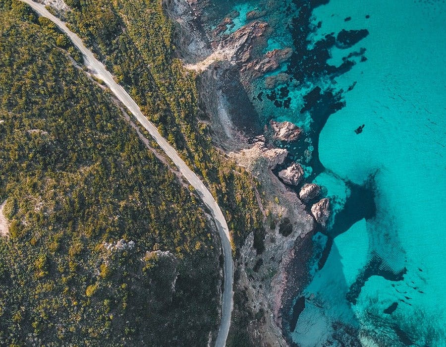 overhead view of turquoise waters off a green mountain