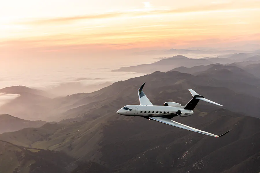 A G650 airplane flying over mountainous ground