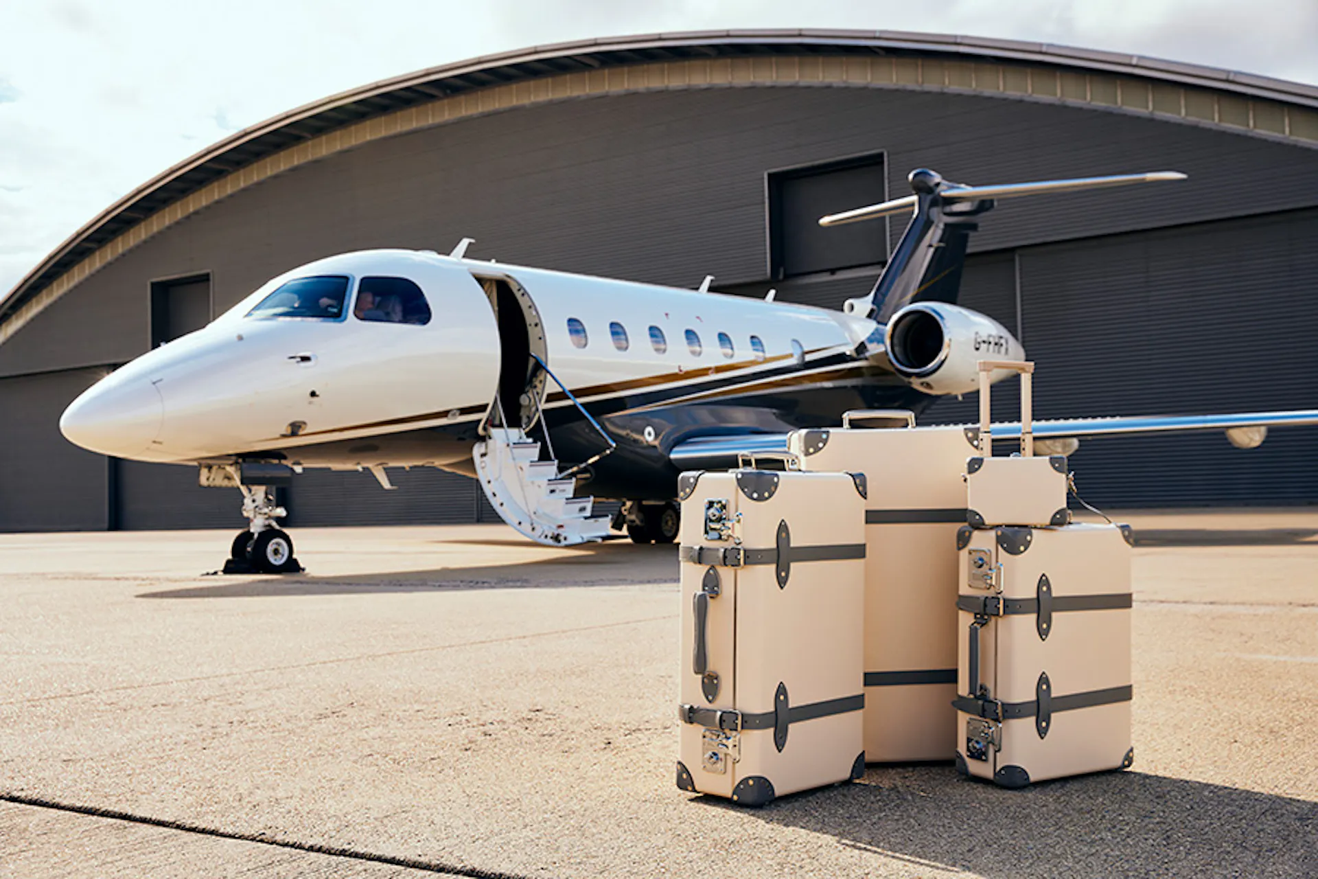A Flexjet aircraft on the tarmac with a hangar behind with luggage in the foreground