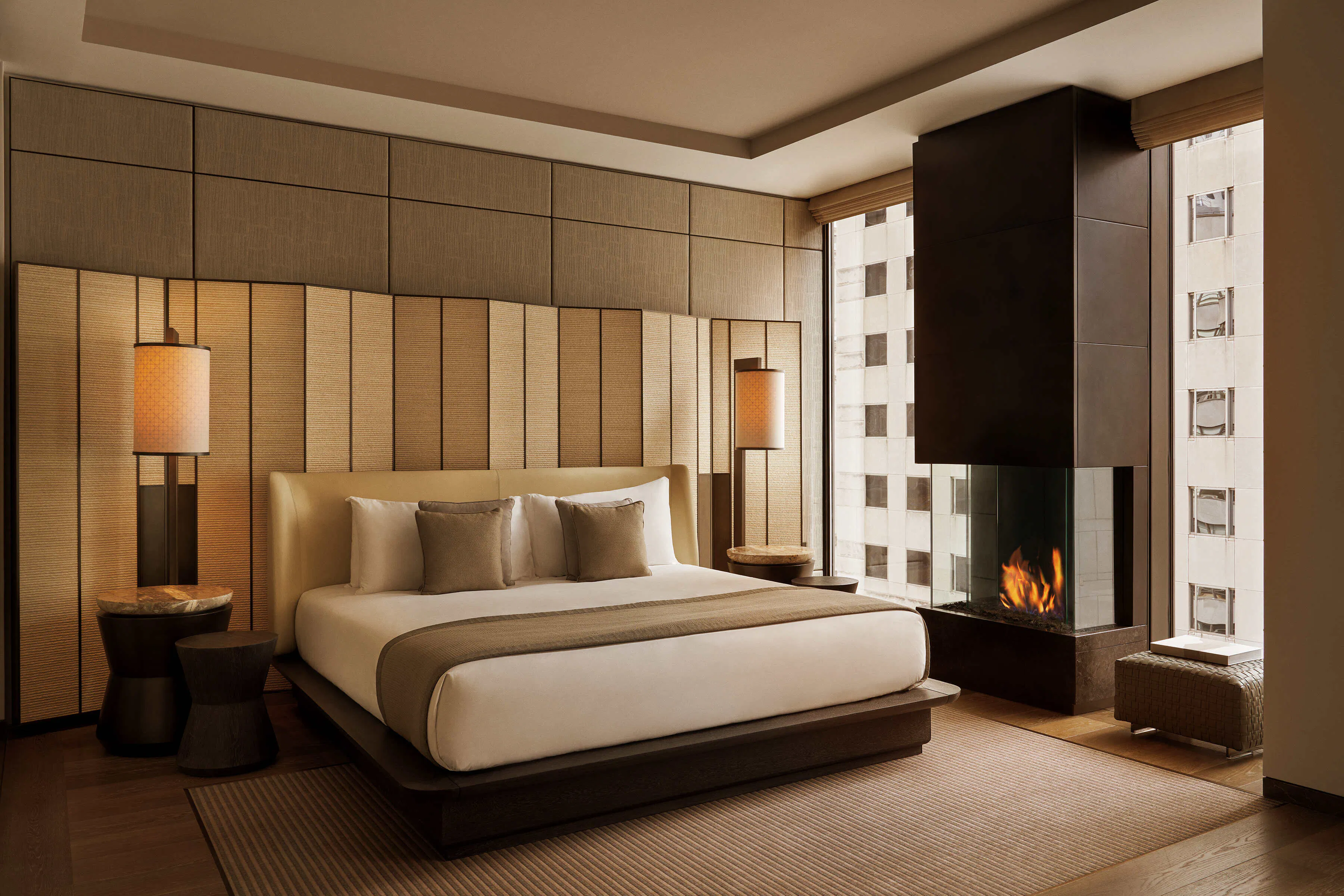 Luxury suite with made bed and a fire place between windows on a higher up floor