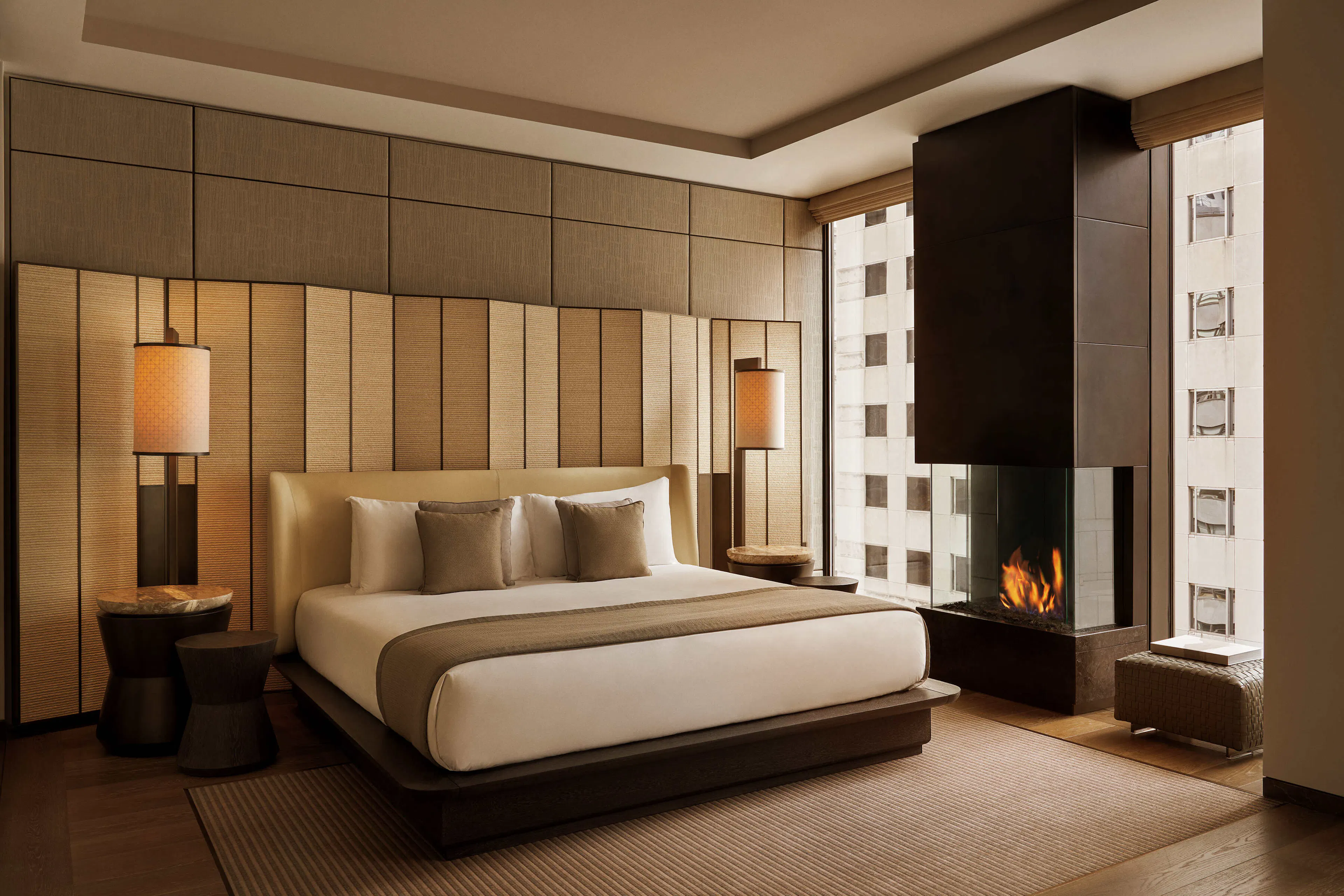 Luxury suite with made bed and a fire place between windows on a higher up floor