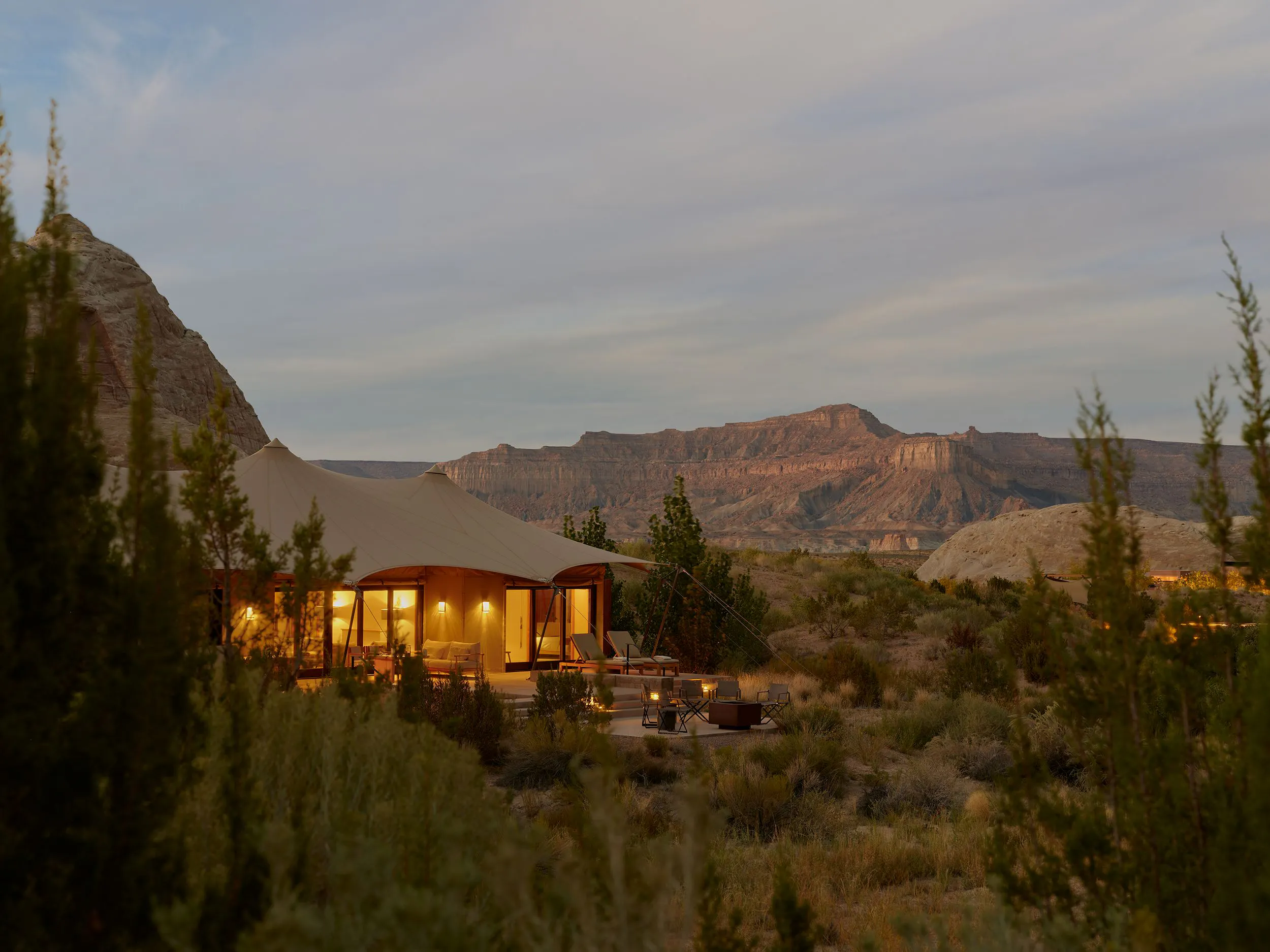 desert mountains and plant life surround a luxury cabin illuminated by lights