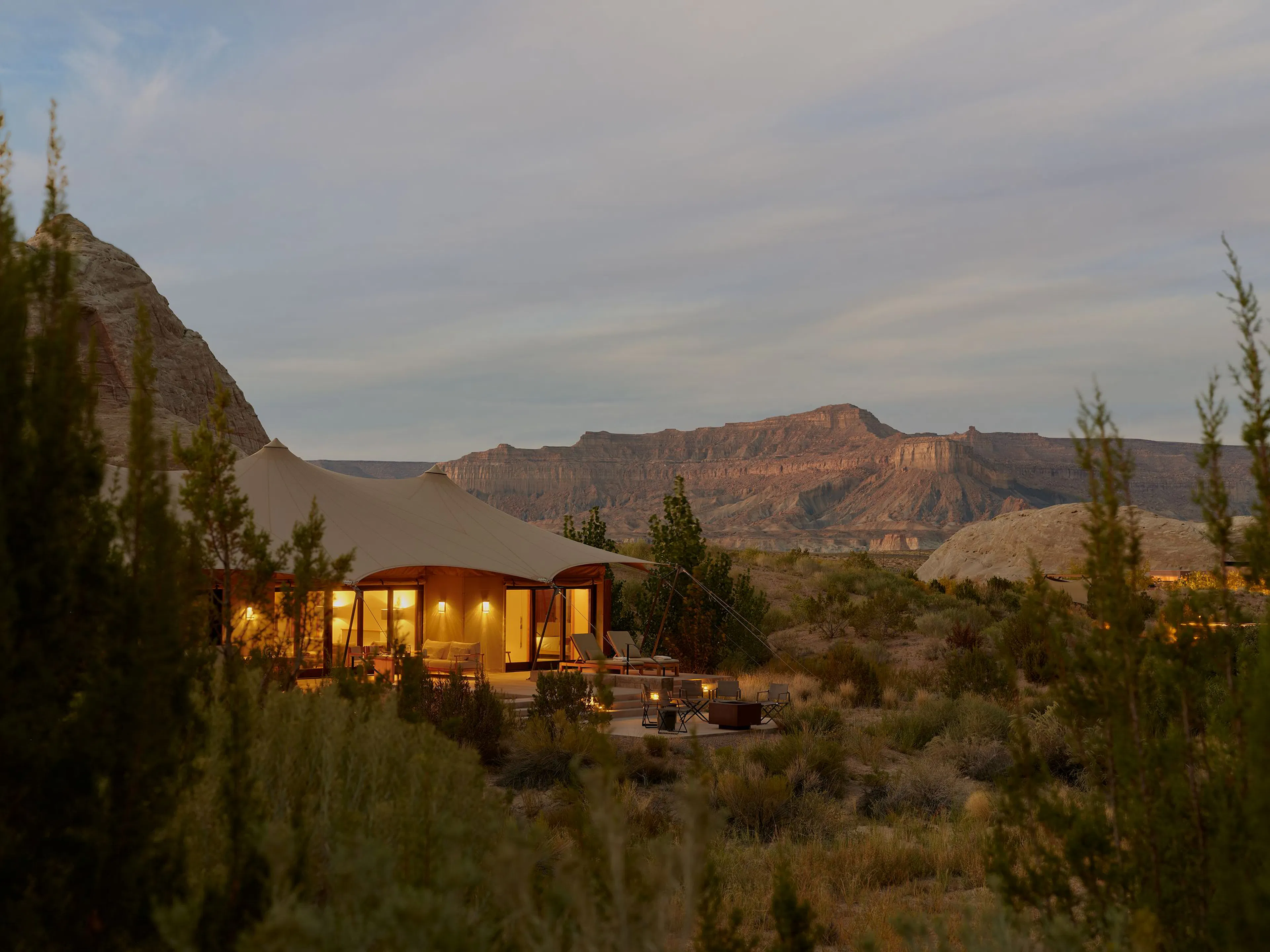 desert mountains and plant life surround a luxury cabin illuminated by lights