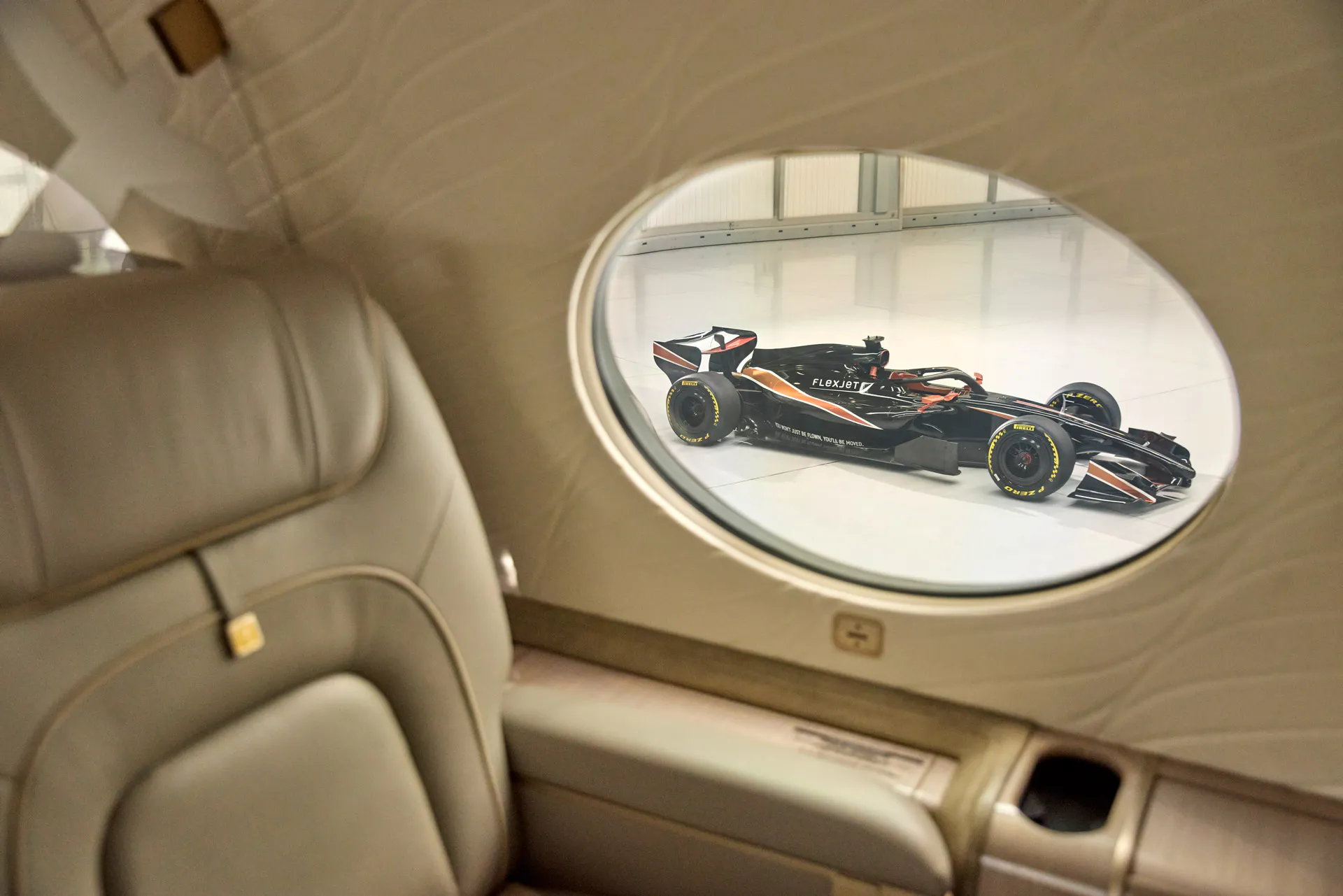Interior of a Flexjet Aircraft with an F1 car viewable through a rounded window