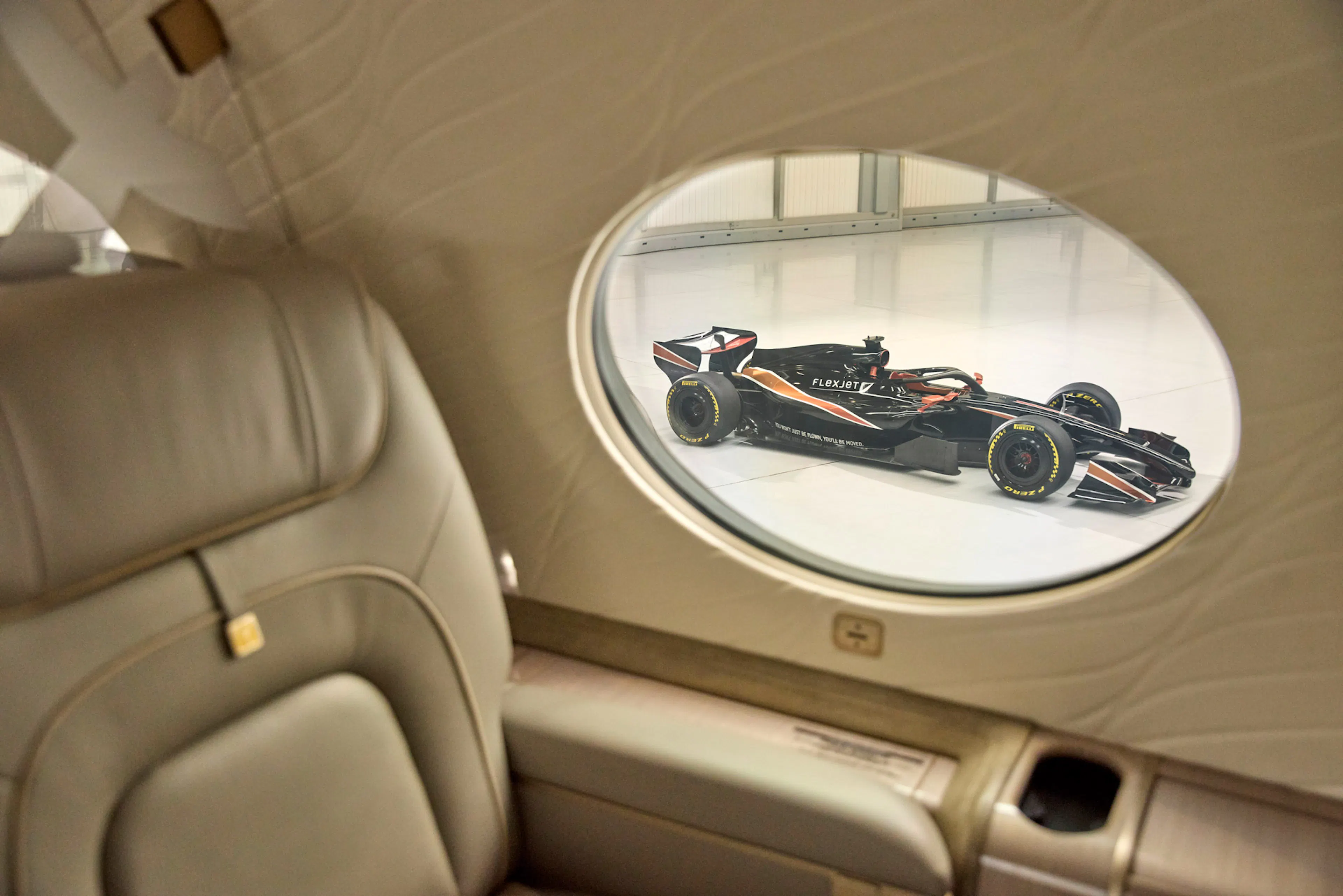 Interior of a Flexjet Aircraft with an F1 car viewable through a rounded window