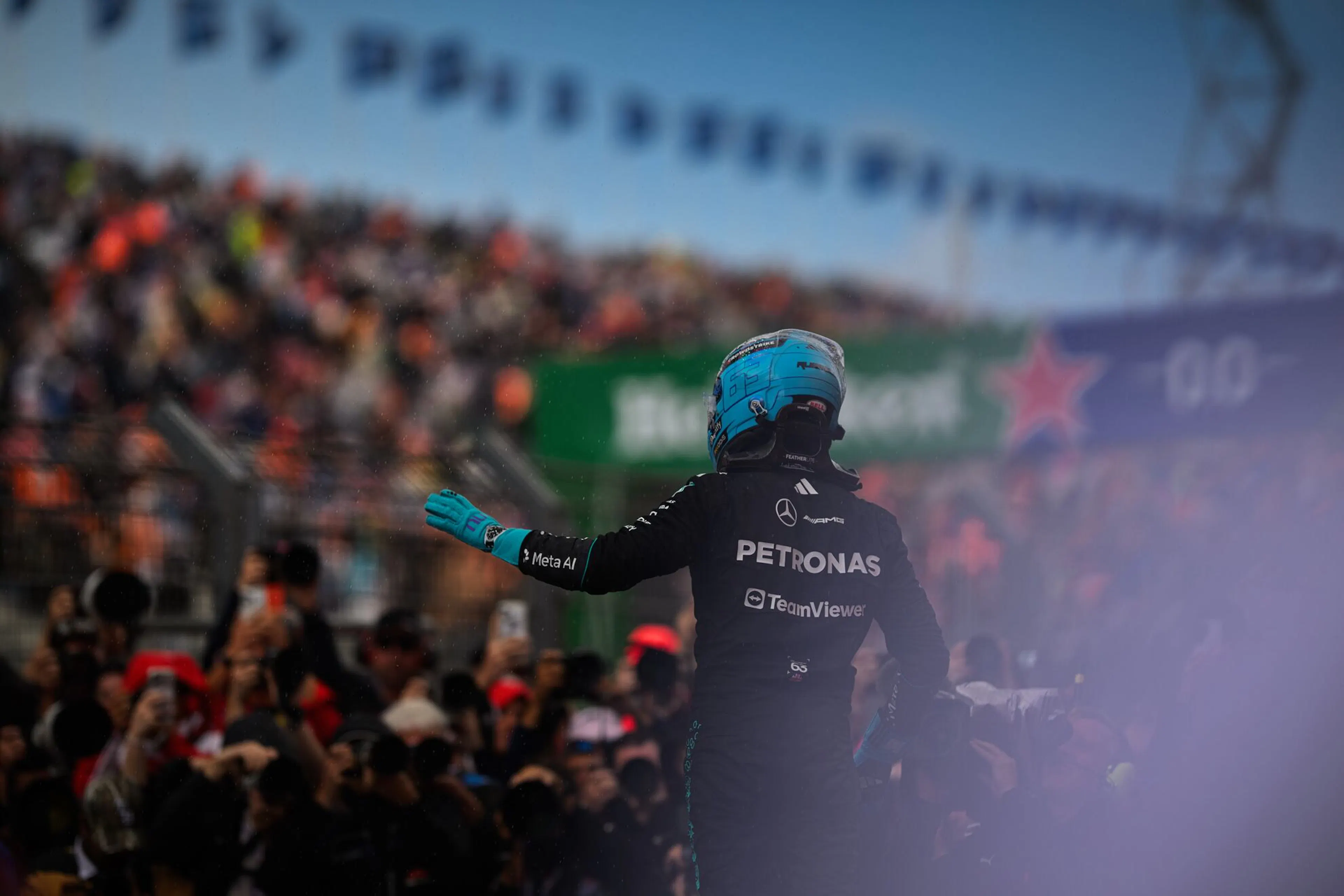 Celebration of a driver with a teal helmet and gloves as the crowd takes pictures