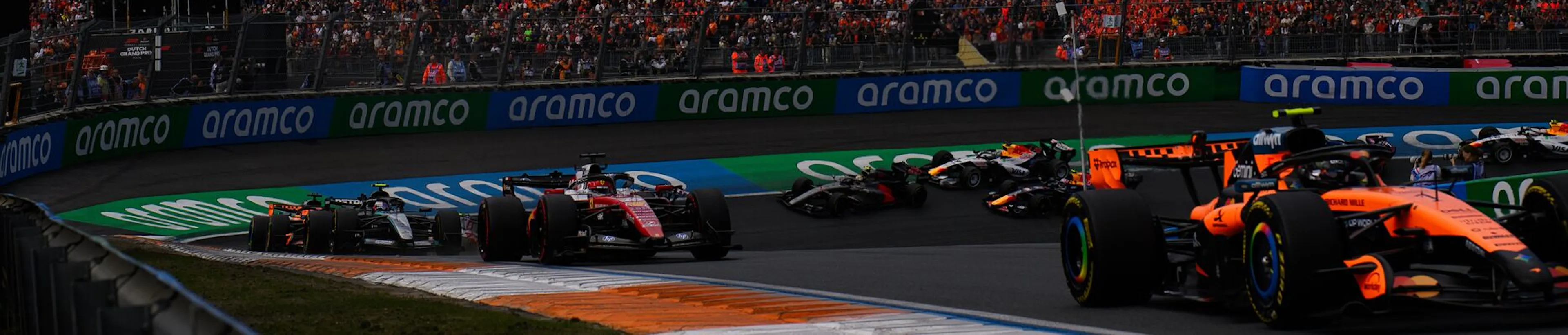 Crowd in the stands watching F1 cars zip around a corner