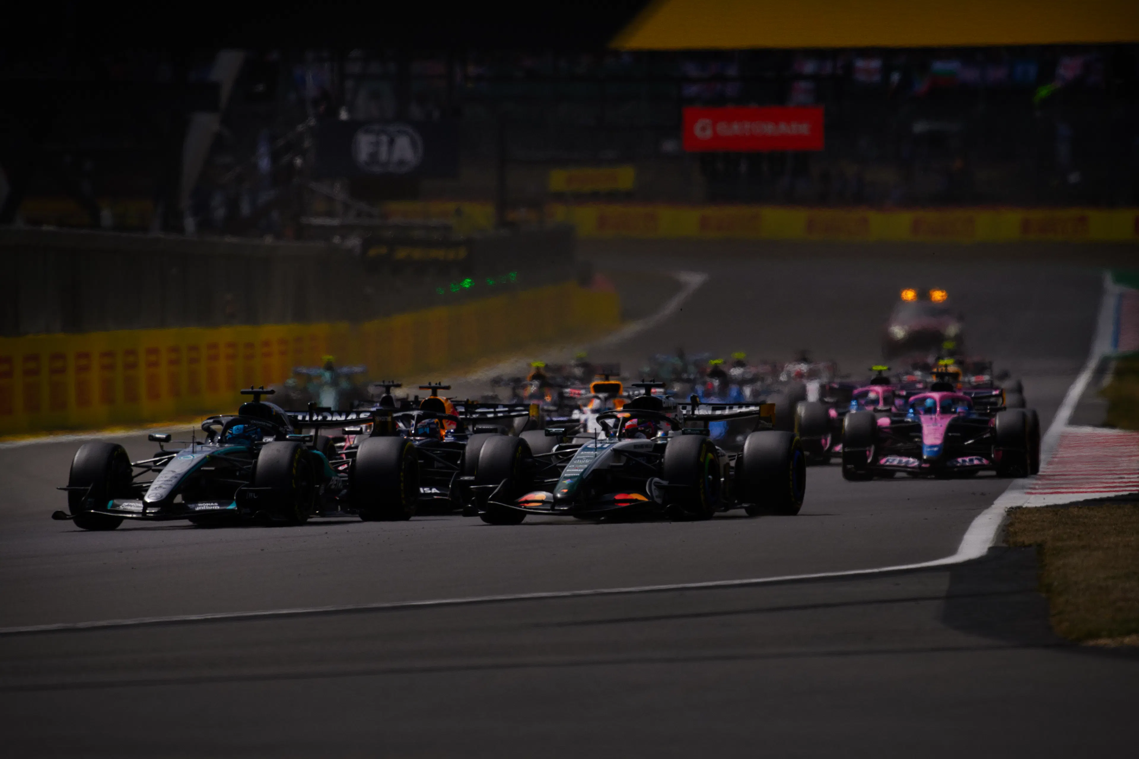 A number of F1 cars driving on the track around a turn