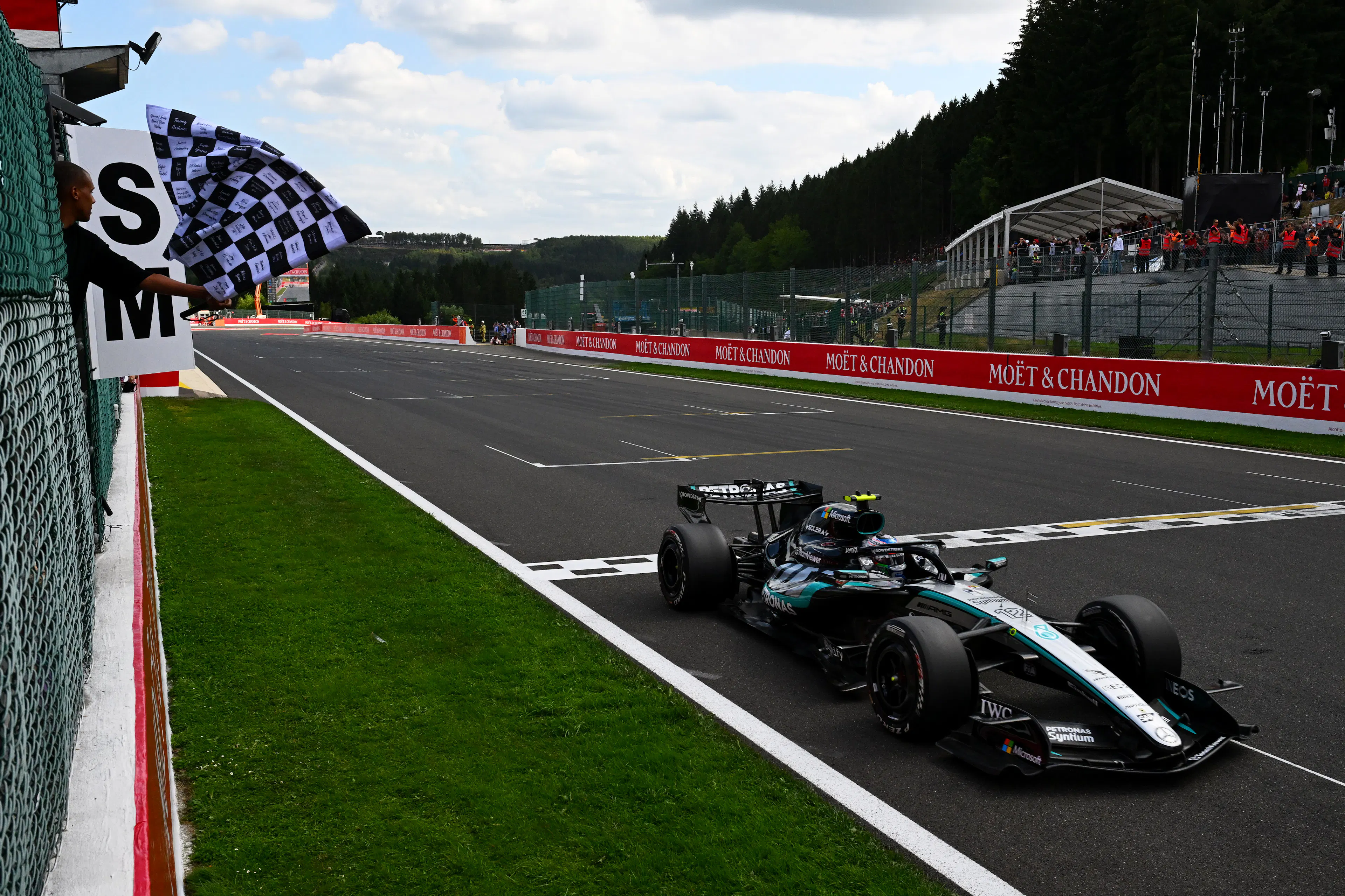 F1 racecar crossing the finish line with a checkered flag waving