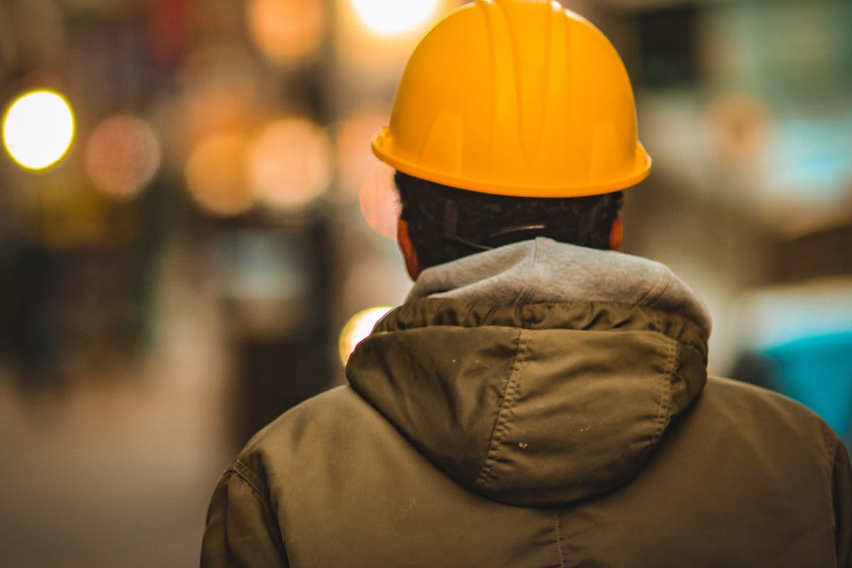 gewerblicher Angestellter von hinten mit Bauarbeiterhelm gewerblicher Angestellter von hinten mit Bauarbeiterhelm