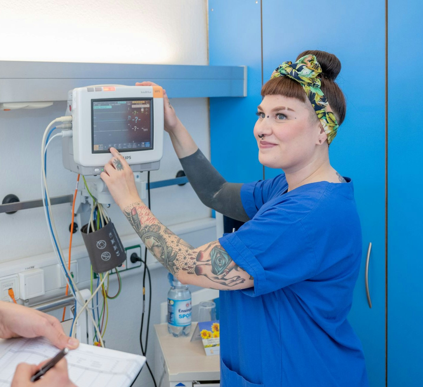 Krankenschwester in blauer Dienstkleidung bedient Überwachungsmonitor