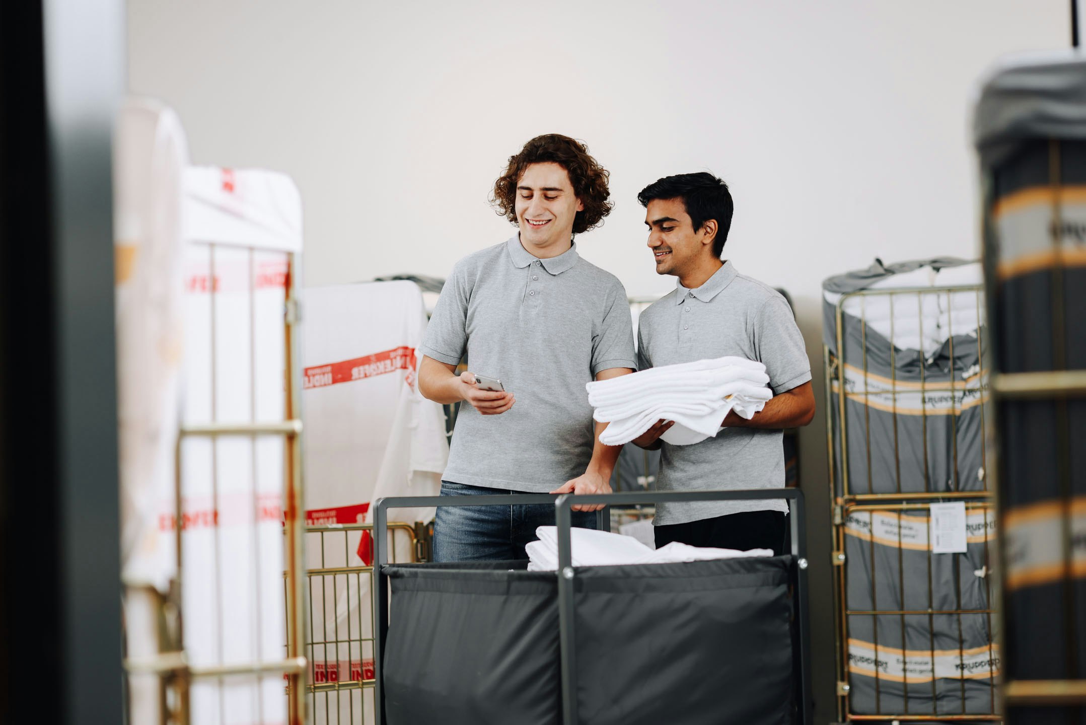 Two service staff in the laundry look into a smartphone