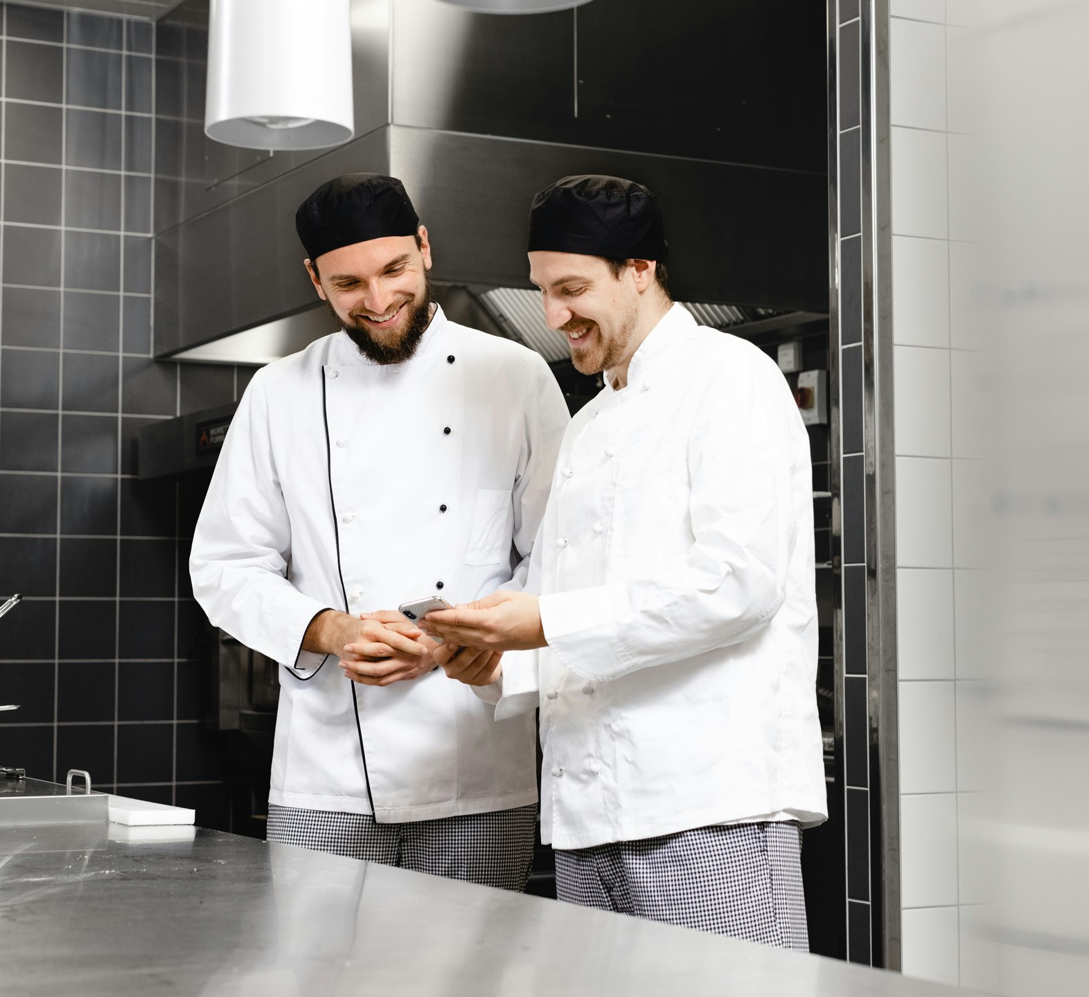 Two employees standing in the kitchen looking at a phone