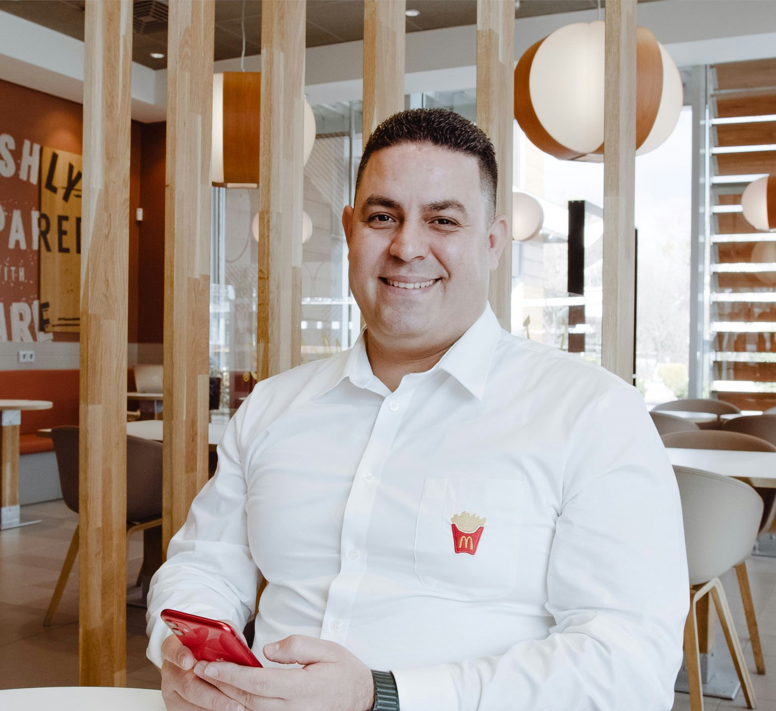 McDonald's employee smiling and using his smartphone