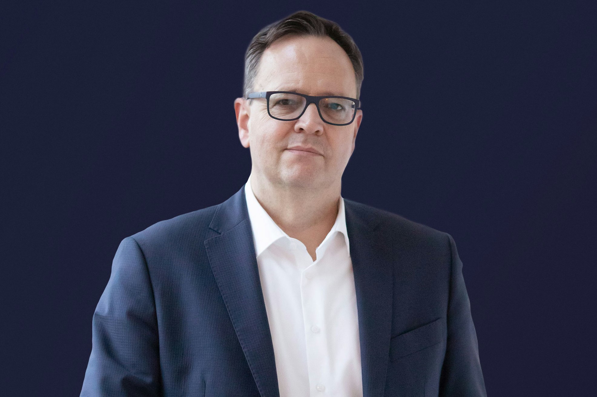 René Haßfeld smiling in suit and wearing glasses