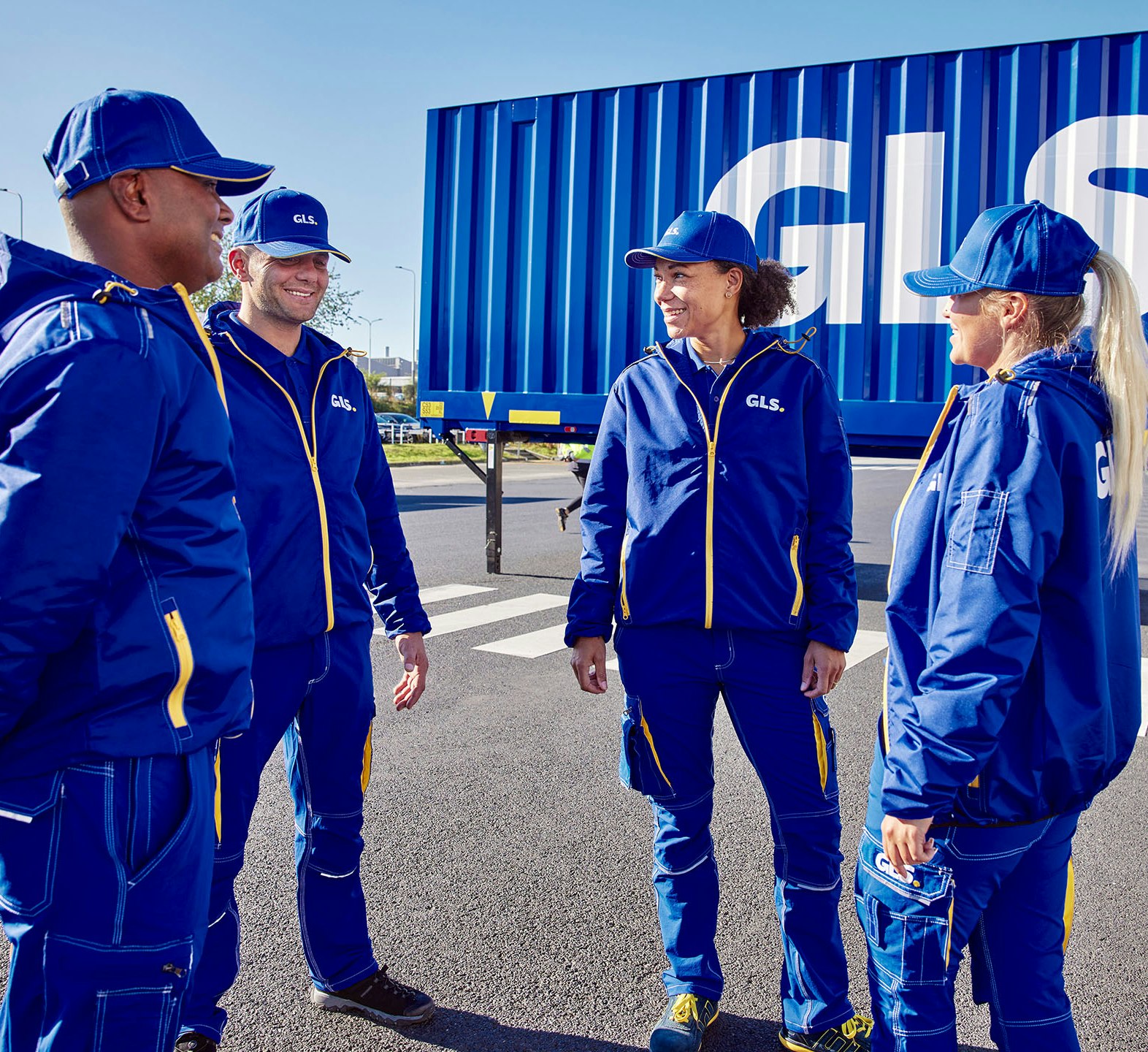 GLS employees stand in front of a truck and smile.