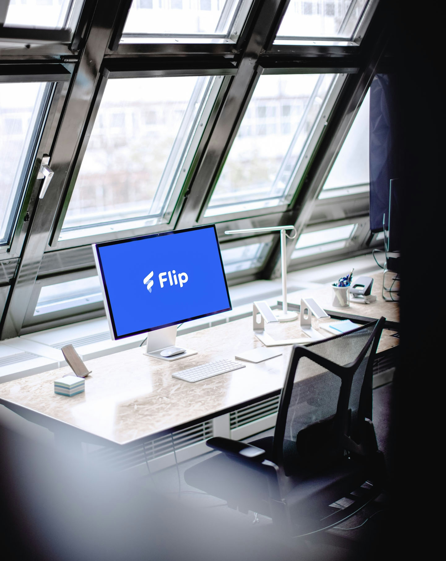 Desk with a screen in front of a big window