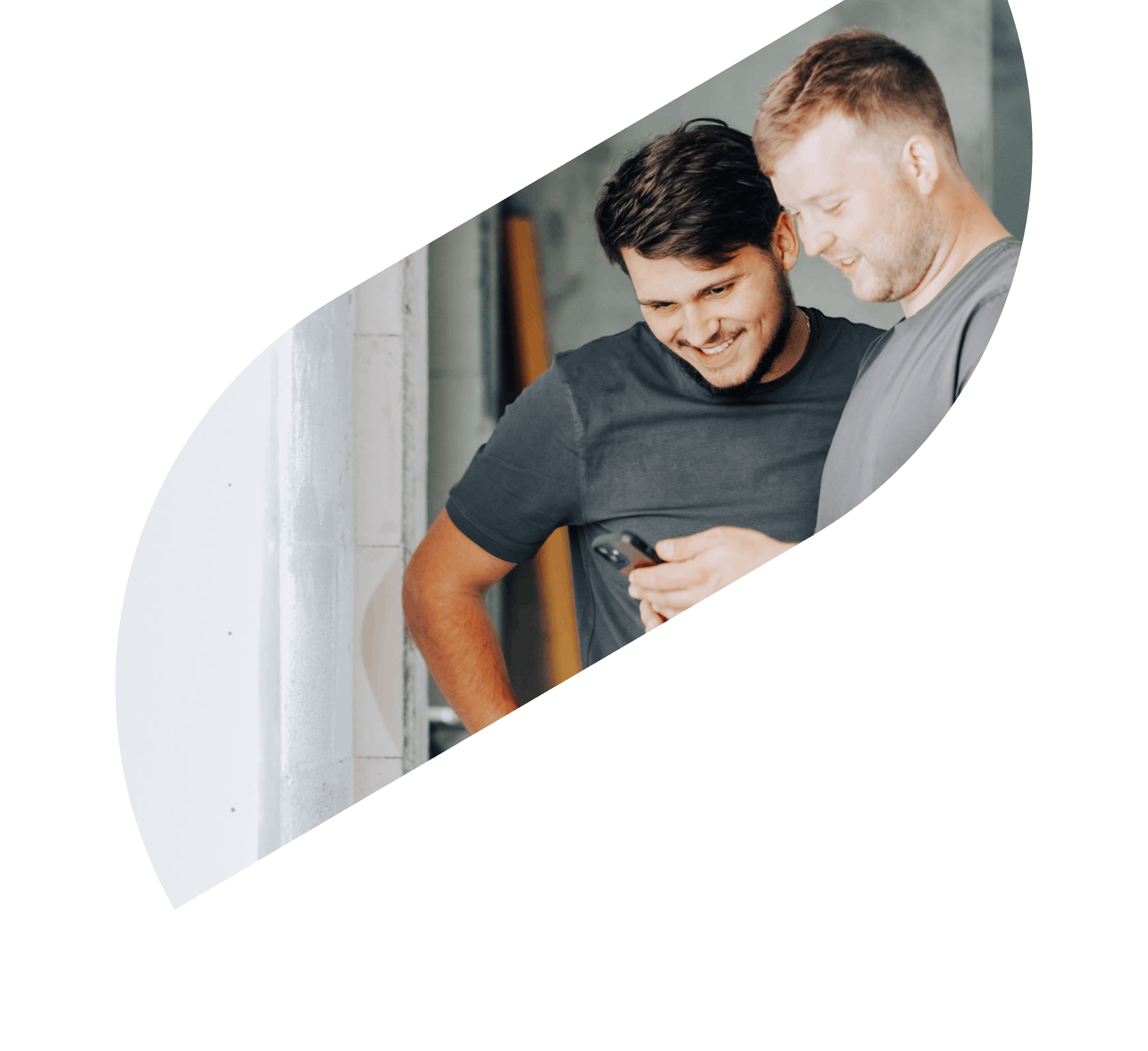 Two construction site workers look at a mobile phone