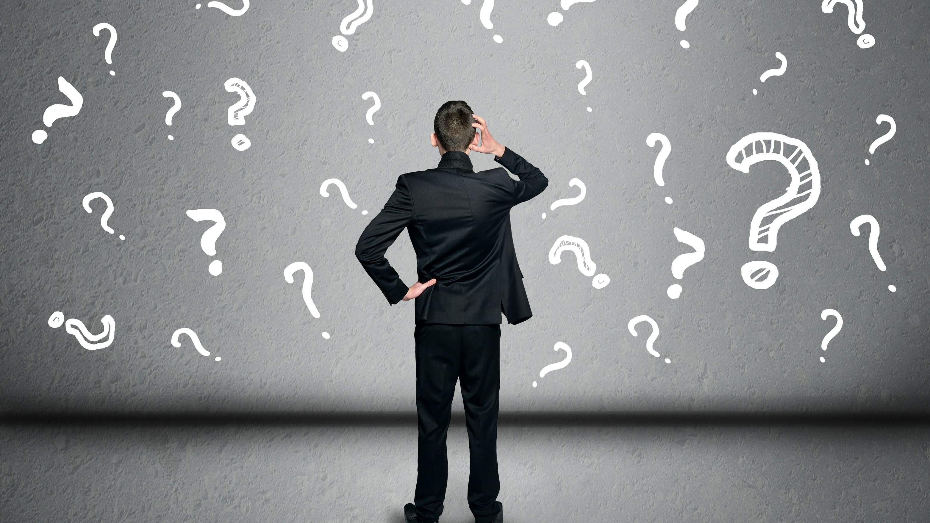 Man standing in front of wall full of question marks