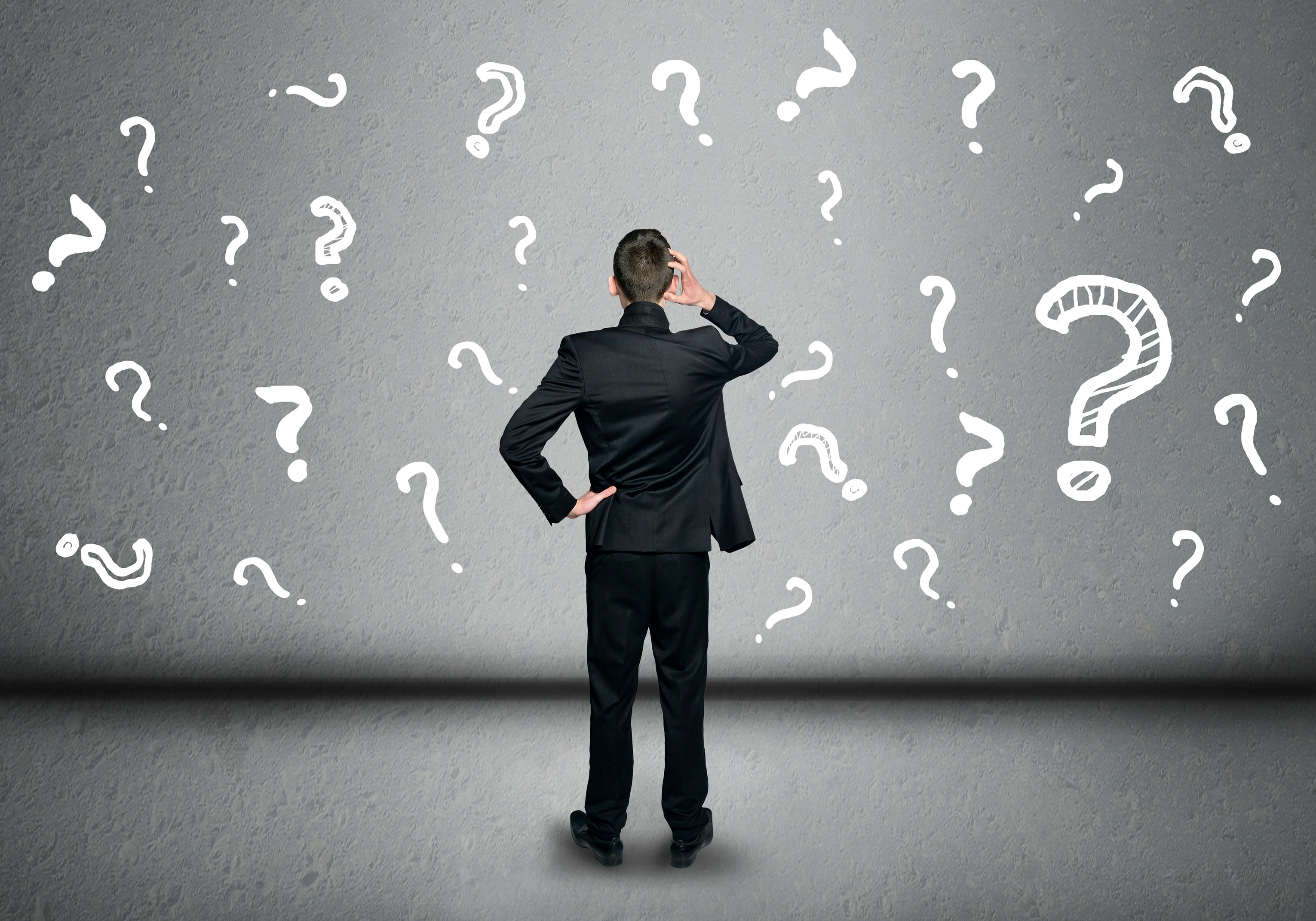 Man standing in front of wall full of question marks