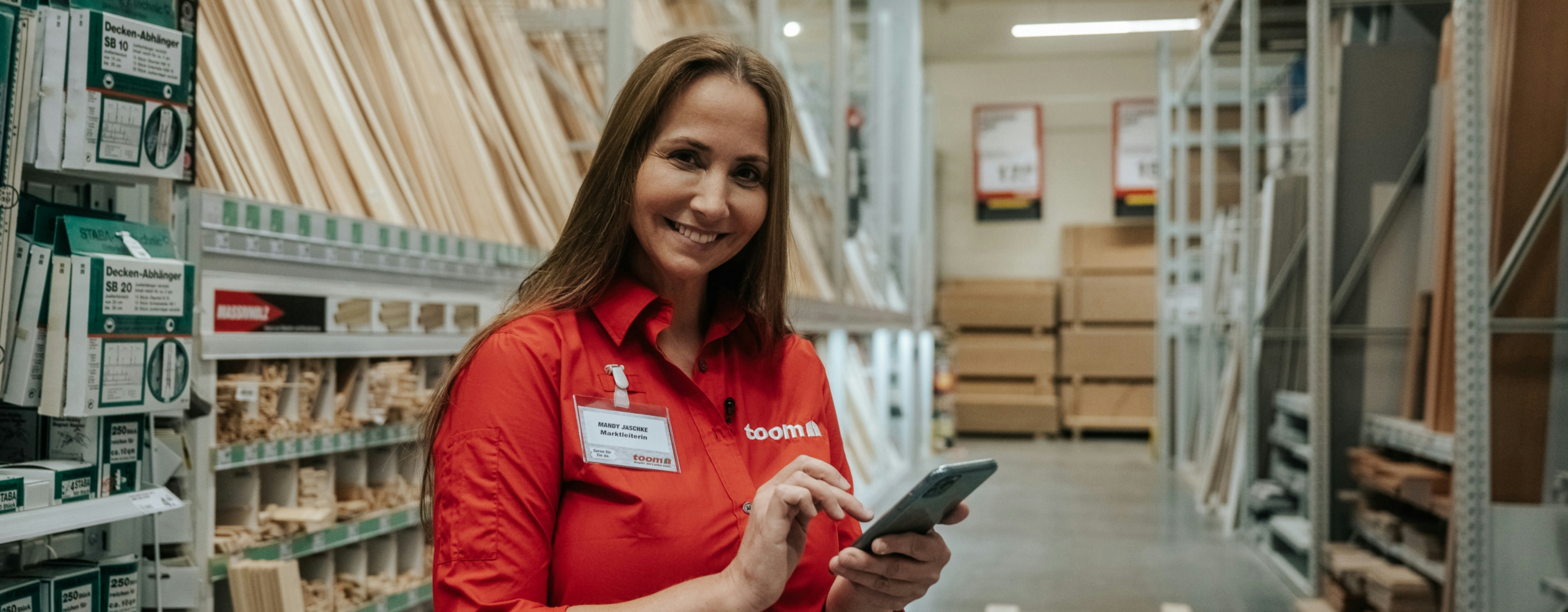 Mandy Jäscke in roter Toom-Bluse mit Smartphone in der Hand