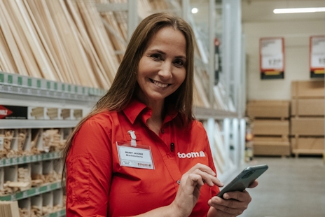 Mandy Jäscke in roter Toom-Bluse mit Smartphone in der Hand