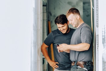 Zwei Bauarbeiter schauen in ein Smartphone