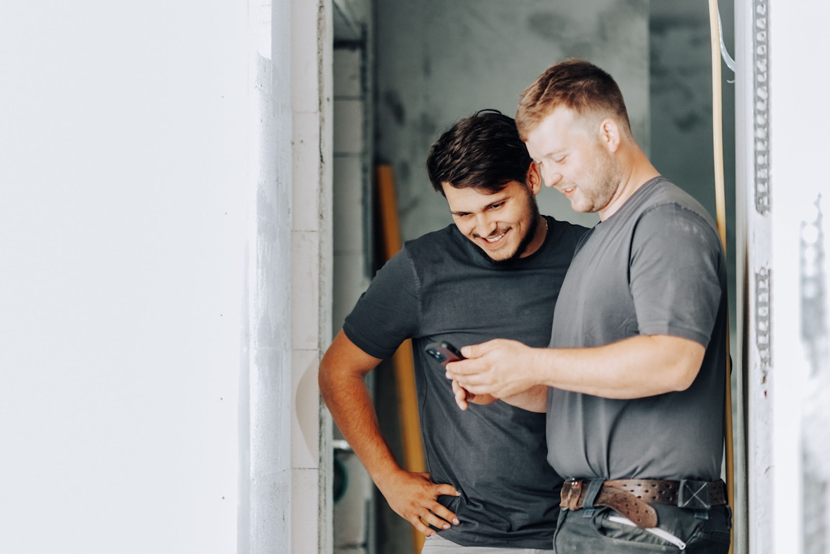 two construction workers looking on a smartphone