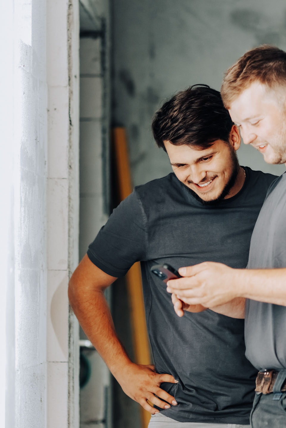 two construction workers looking on a smartphone