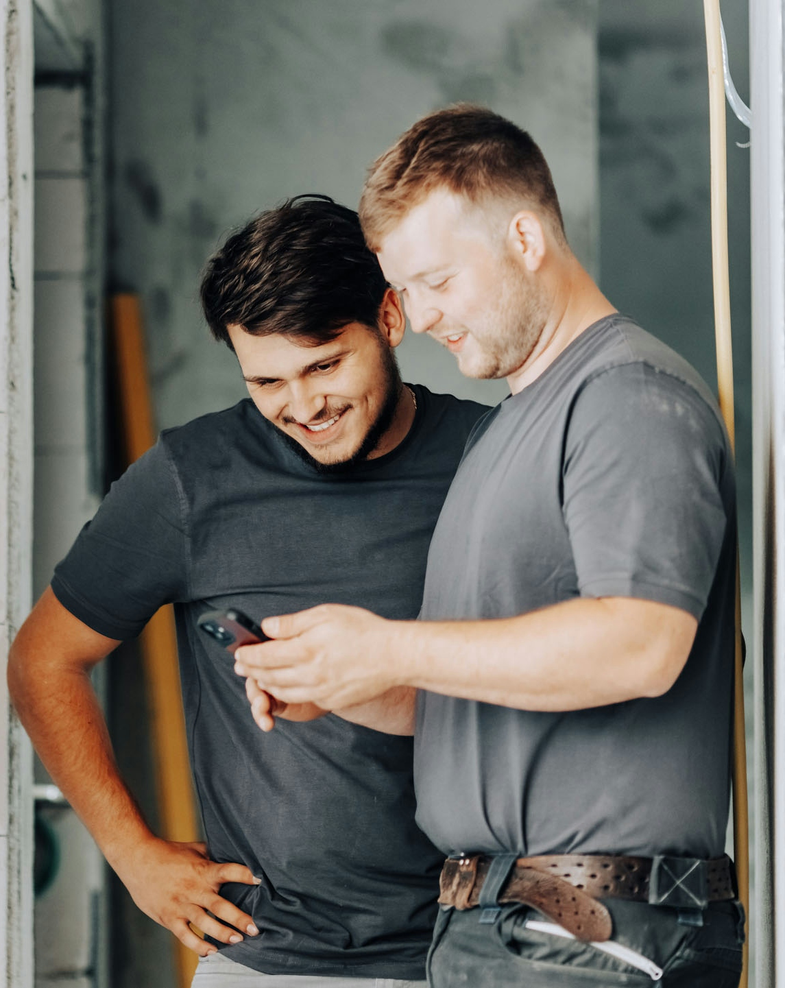 Zwei Bauarbeiter schauen in ein Smartphone
