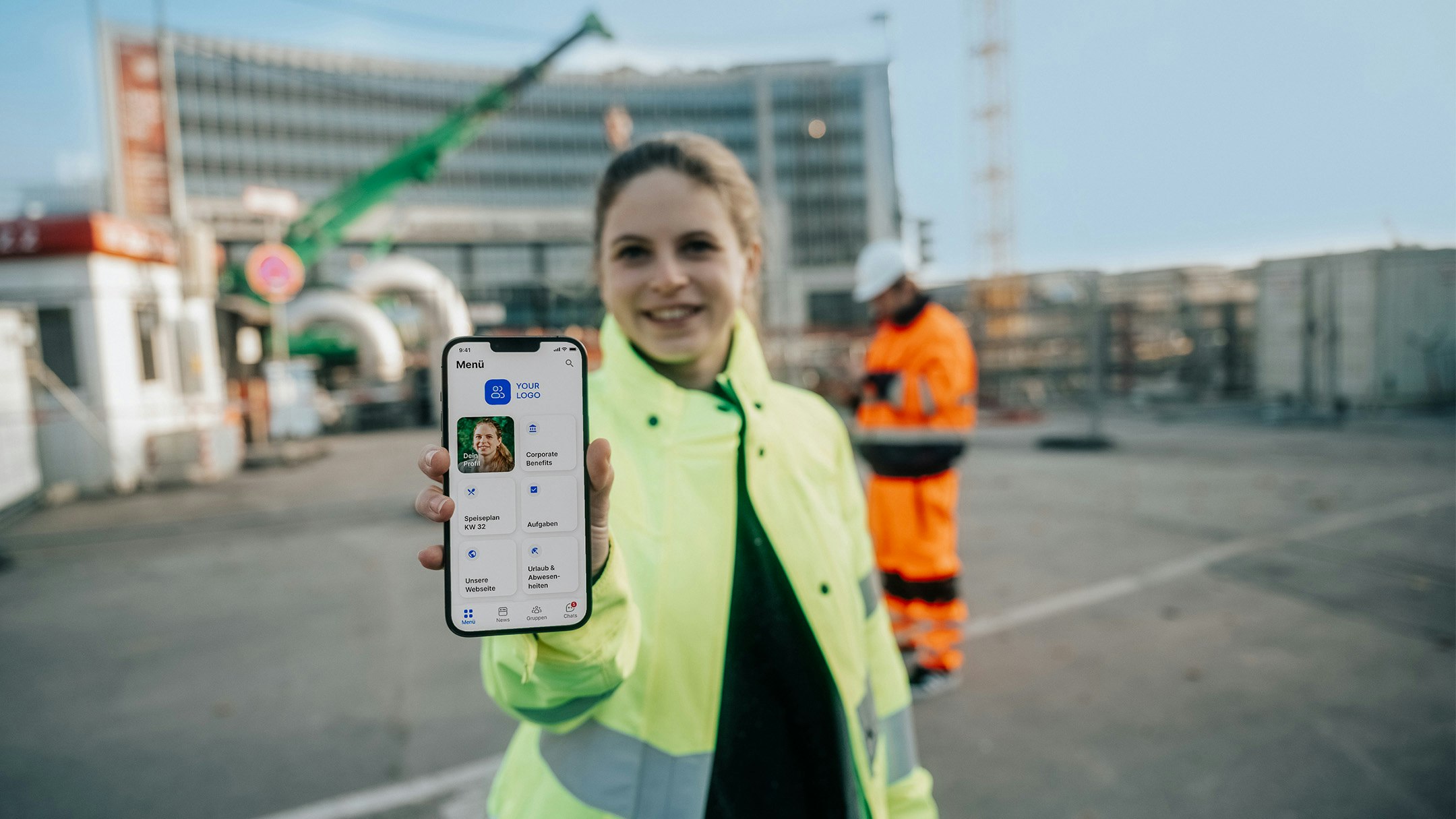 Arbeiterin auf Baustelle zeigt Mitarbeiter-App in die Kamera 