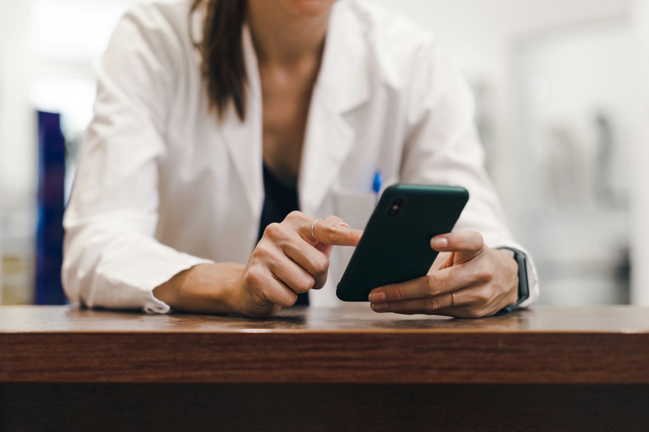 Woman in white work clothes typing into smartphone