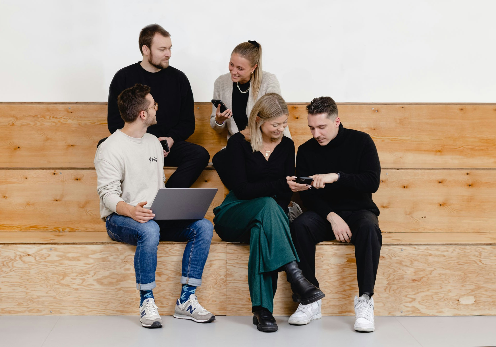 Five people are sitting on wooden stairs and using mobile devices