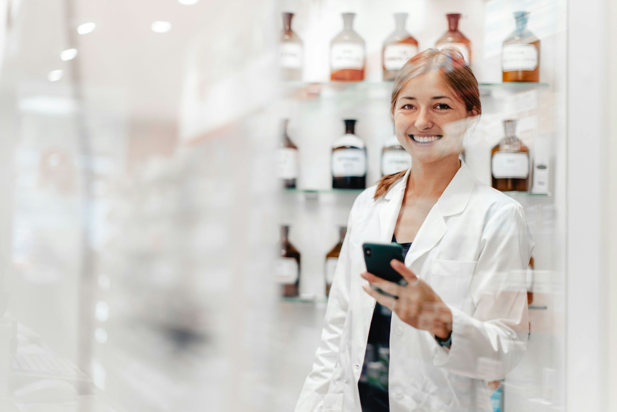 Pharmacist photographed through window with drugs in background