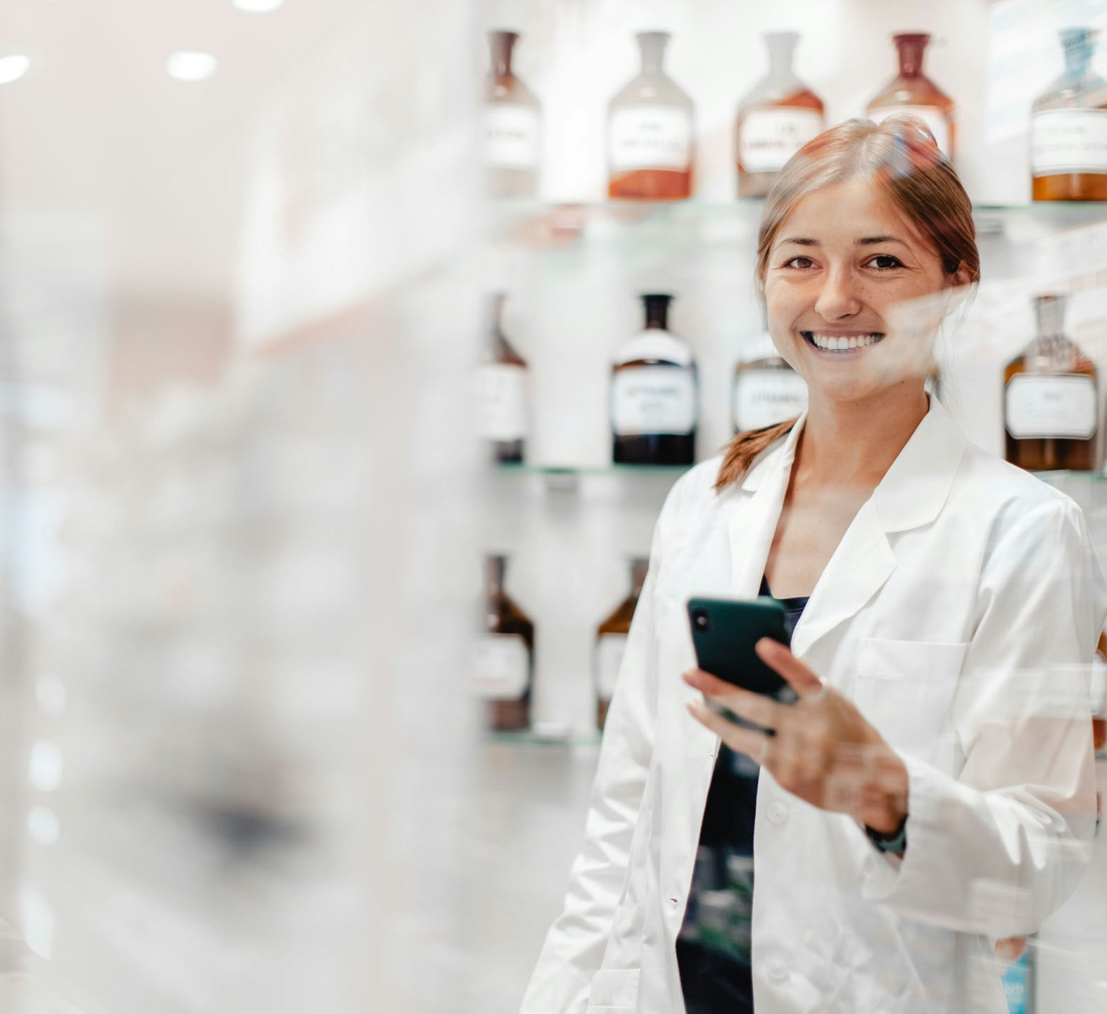 Pharmacist photographed through window with drugs in background