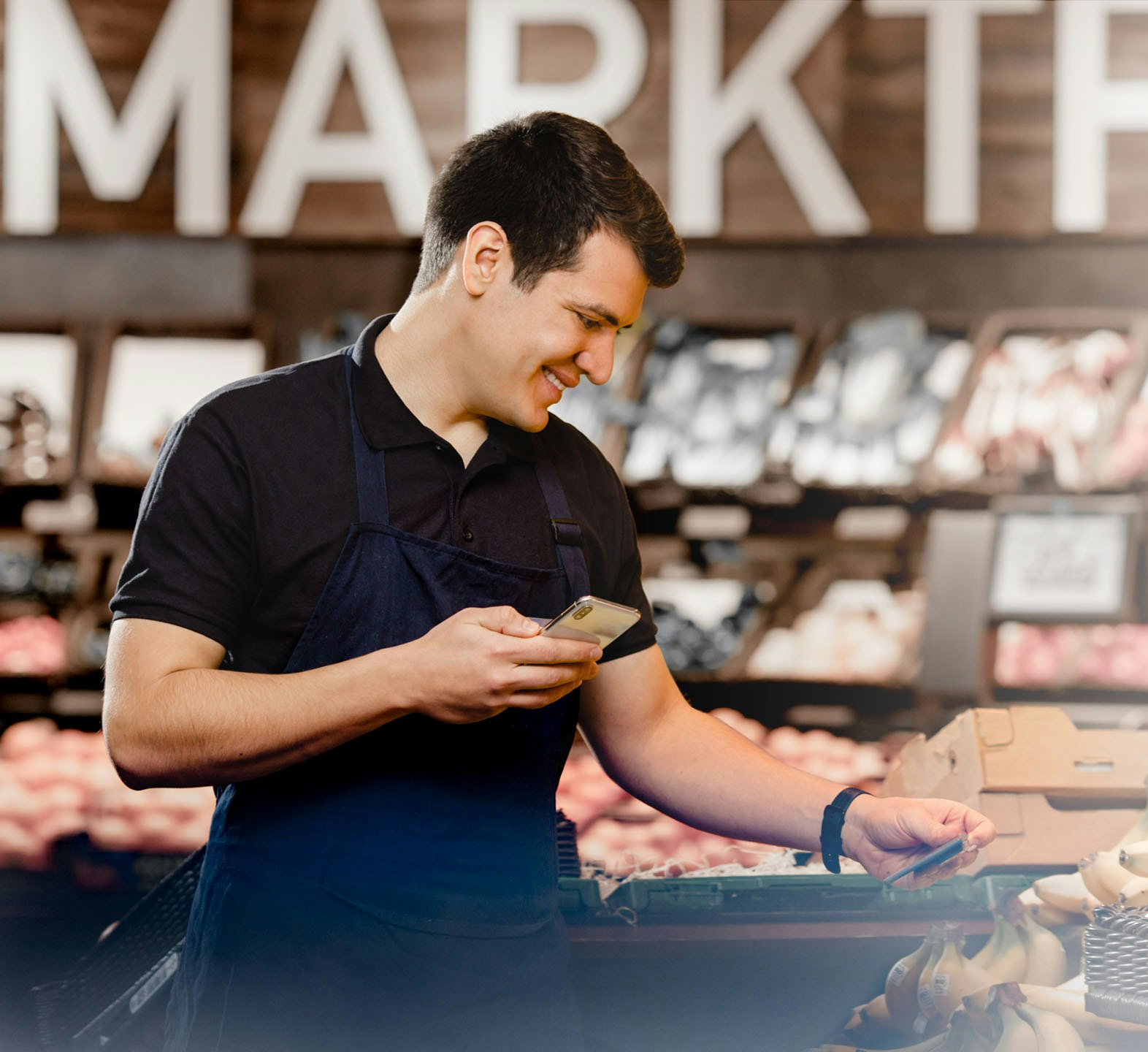 Seller with mobile phone in hand looks at sign in vegetable department