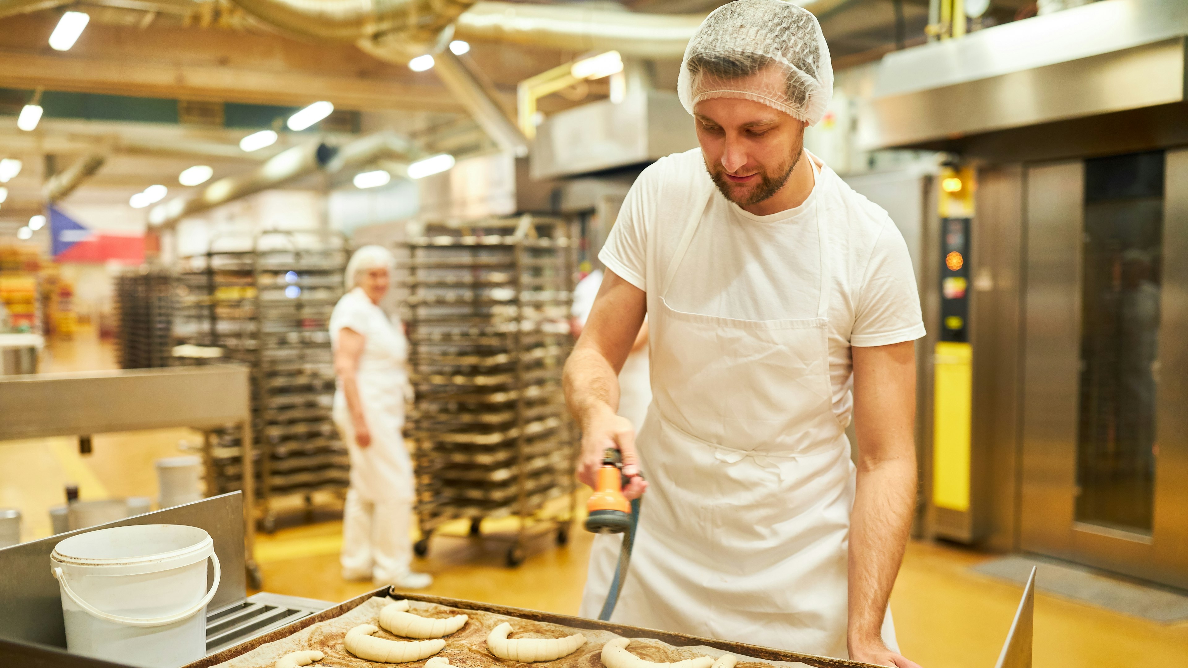 Image of man working in bakery making croissants.