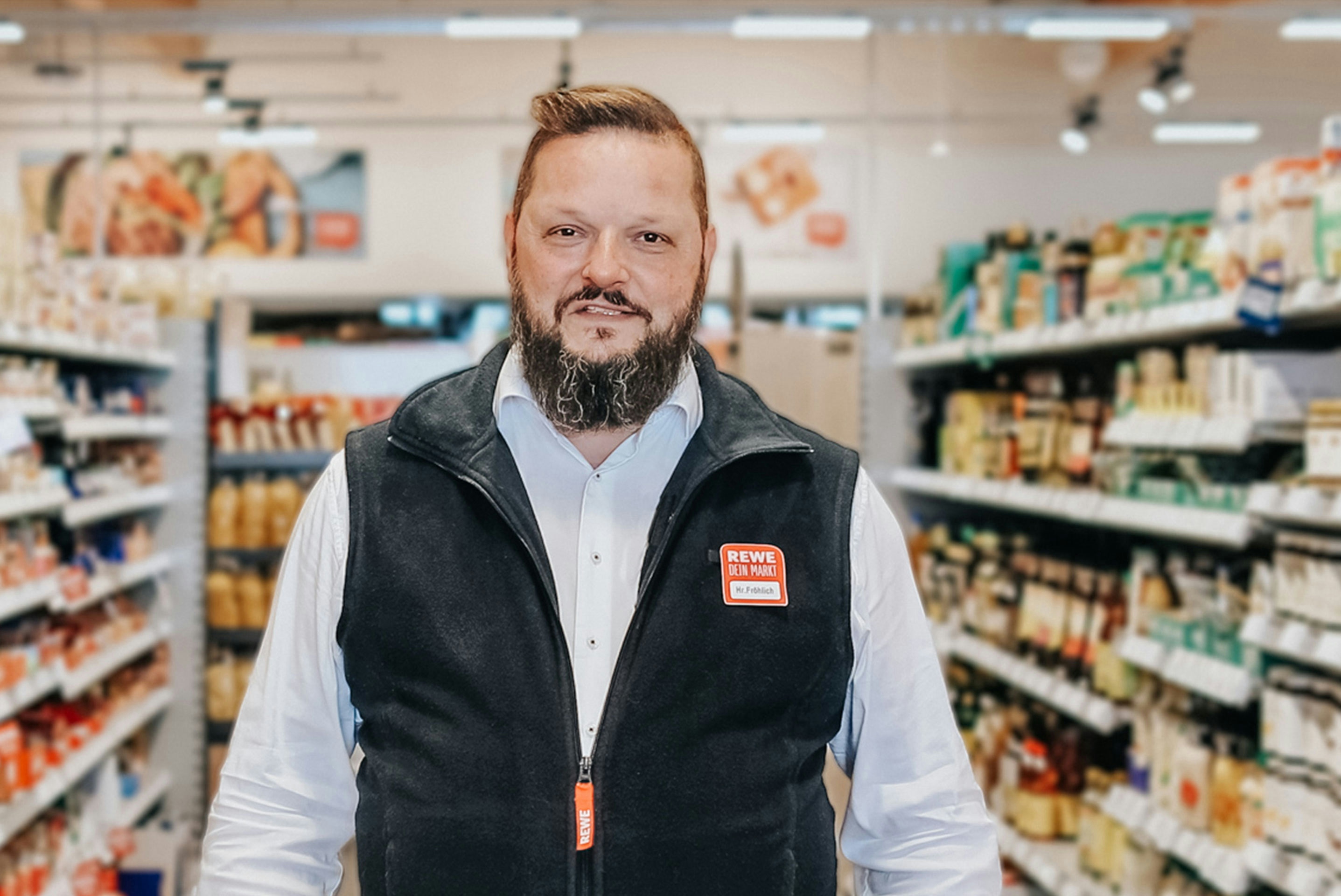 Michael Fröhlich, Kaufmann bei REWE in Hemd und REWE-Weste