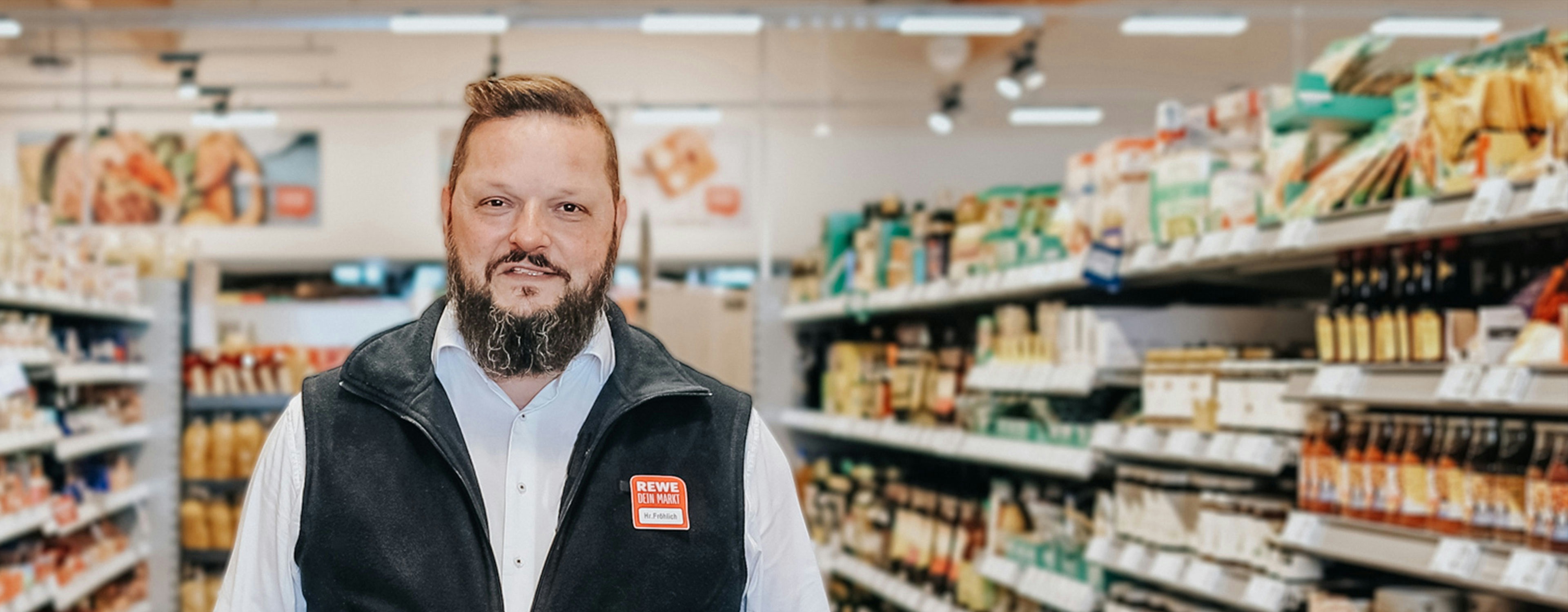 Michael Fröhlich, Kaufmann bei REWE in Hemd und REWE-Weste