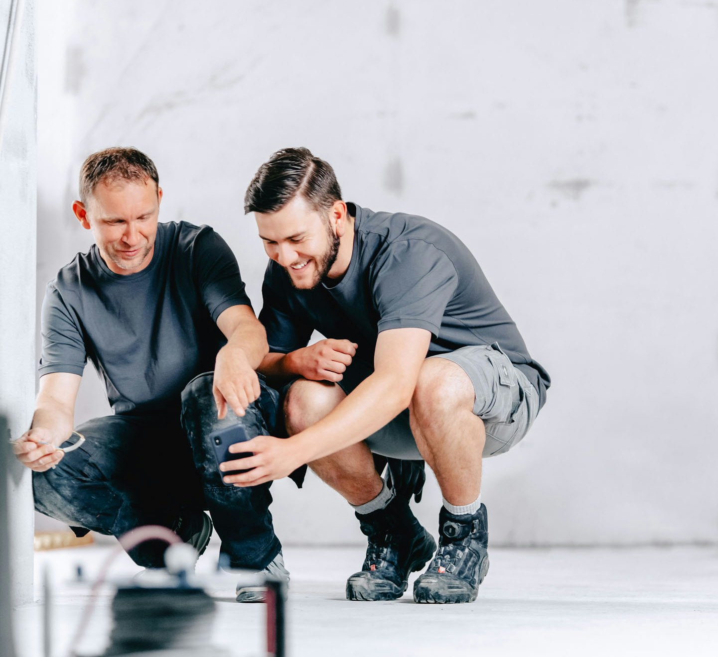 Two construction workers install cables while kneeling